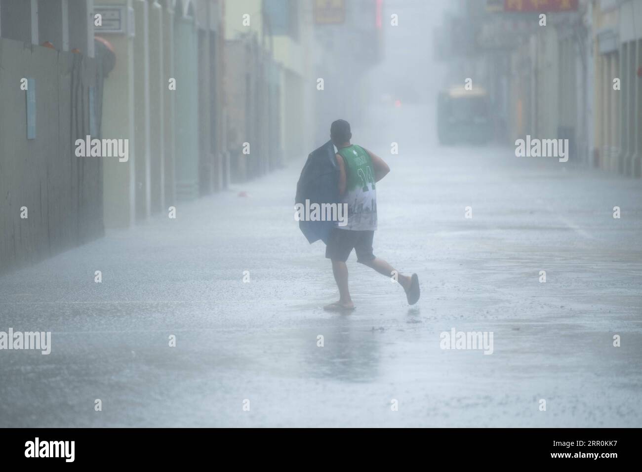 200819 -- MACAO, 19 agosto 2020 Xinhua -- Un uomo cammina sotto la pioggia su una strada a Macao, nel sud della Cina, 19 agosto 2020. La regione amministrativa speciale di Macao in Cina ha declassato il suo segnale di tifone dal livello più alto 10 al numero 8 il mercoledì alle 7:30 ora locale, ma le zone basse vicino alla costa sono state allagate, poiché il tifone Higos aveva sbarcato nella vicina città di Zhuhai la mattina. Il Macao Meteorological and Geophysical Bureau aveva aggiornato il suo segnale tifone al livello No.10 il mercoledì alle 5:00 am ora locale, prima di declassarlo al No.8 più tardi. L'allarme rosso di tempesta Foto Stock