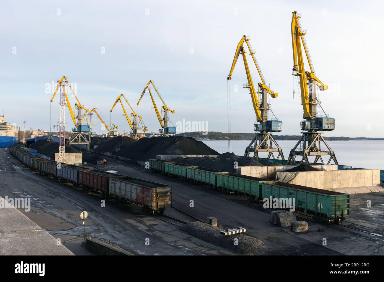 Terminal del carbone di Vyborg. Gru e vagoni ferroviari si trovano sulla riva accanto a pile di carbone per il carico sulle navi Foto Stock