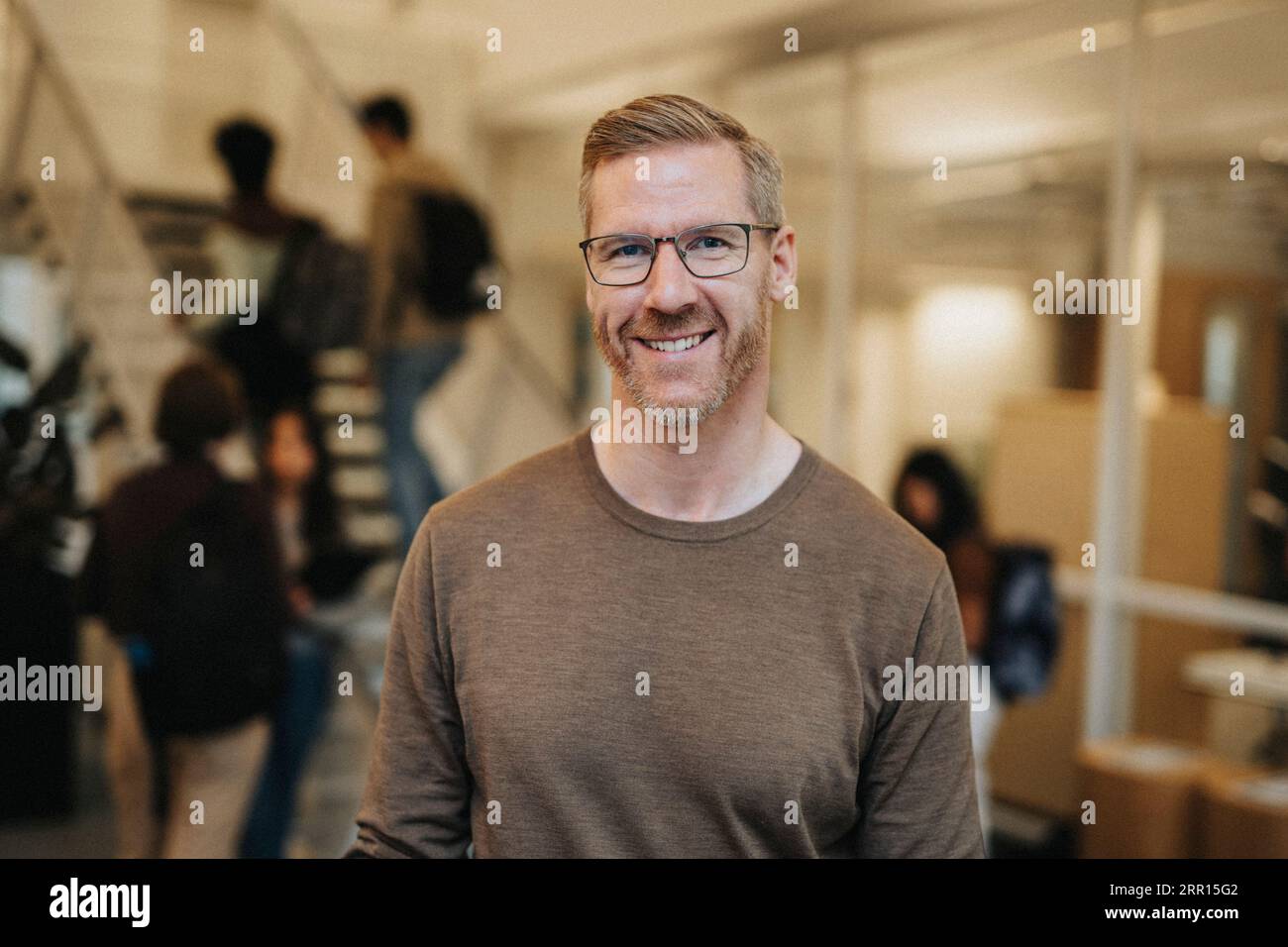 Ritratto di un professore maturo sorridente in piedi all'università Foto Stock