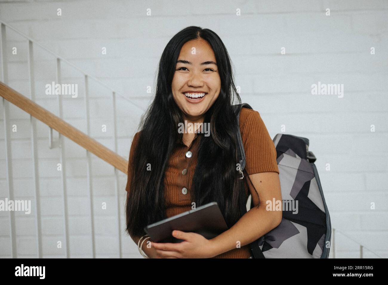 Ritratto di uno studente allegro che porta zaino in piedi all'università Foto Stock