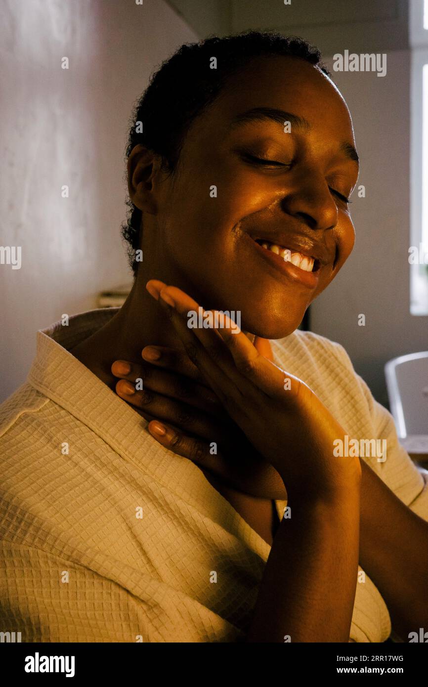 Giovane donna sorridente che indossa l'accappatoio in bagno Foto Stock
