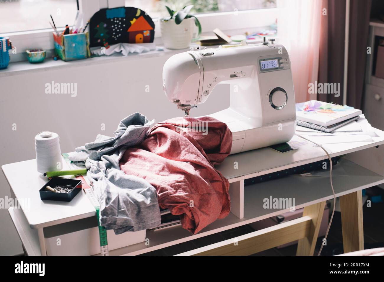 Macchina da cucire con vestiti sul tavolo Foto Stock