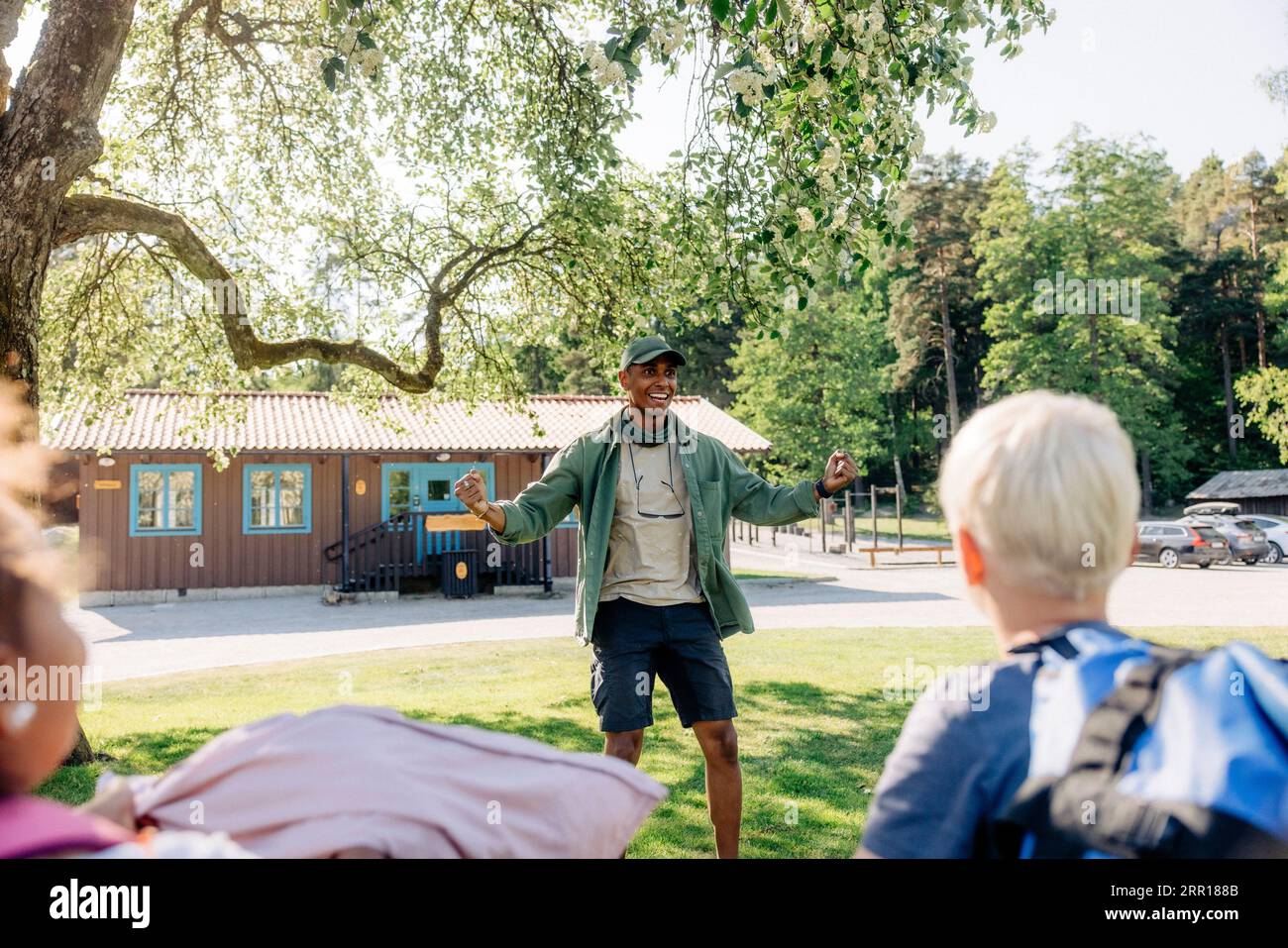 Entusiasta consulente del campo maschile che incoraggia i bambini al campo estivo Foto Stock