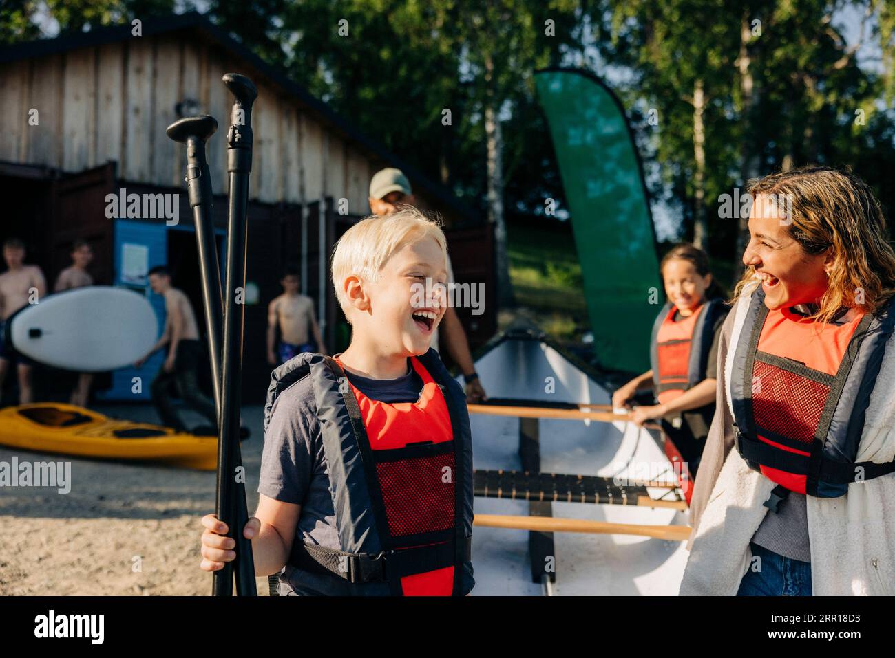 Ragazzo felice con un consulente che indossa giubbotti salvagente mentre va in kayak al campo estivo Foto Stock