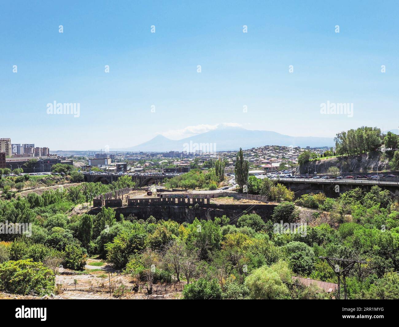 Erevan, Armenia - 26 agosto 2023: Vista della gola di Hrazdan con la fabbrica di brandy NOY nella città di Erevan e il monte Ararat dalla via Sergey Parajanov al sole Foto Stock