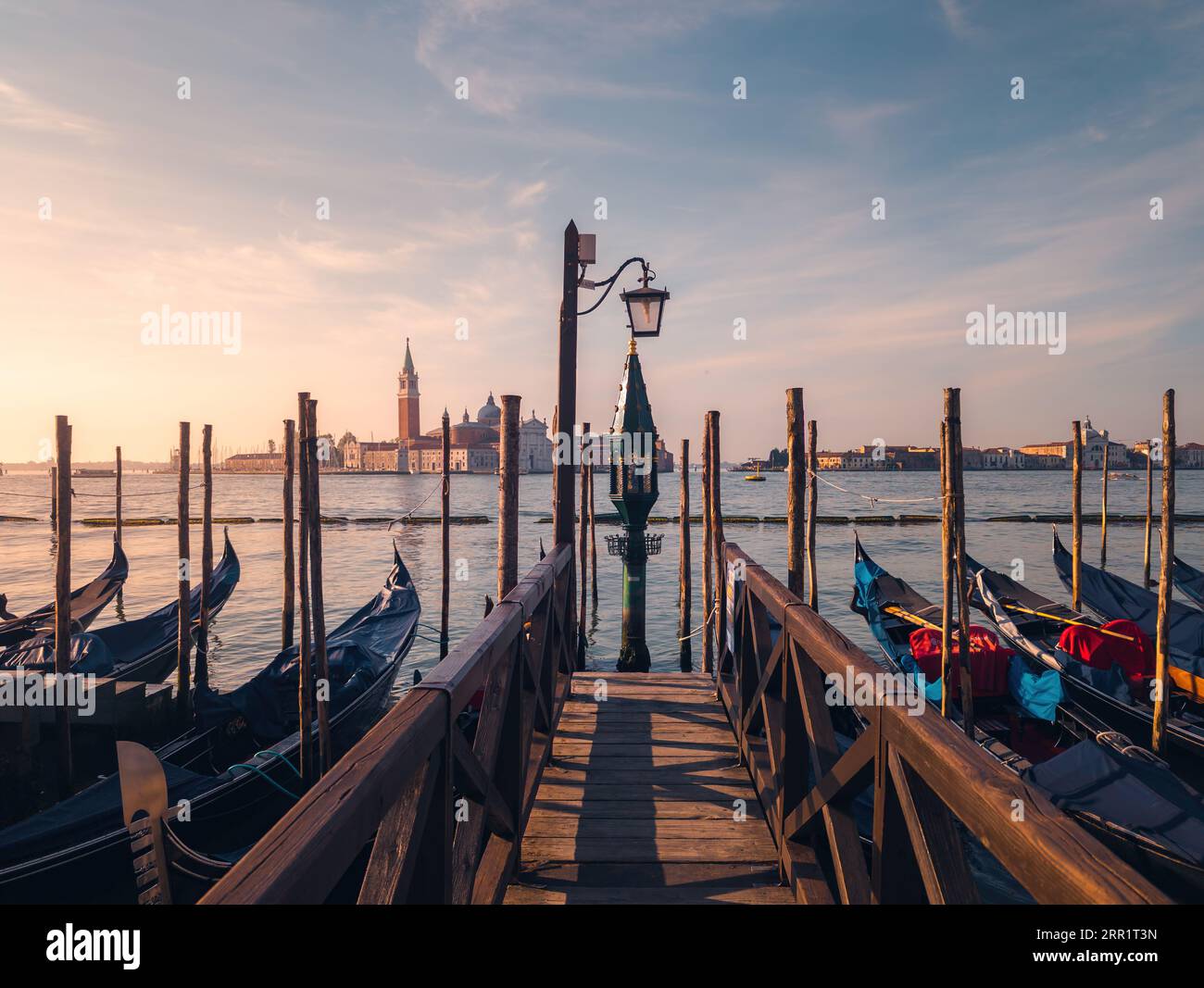 Vista mozzafiato del porto con gondole ancorate contro antichi palazzi e case nel Canal grande del fiume a Venezia al tramonto Foto Stock