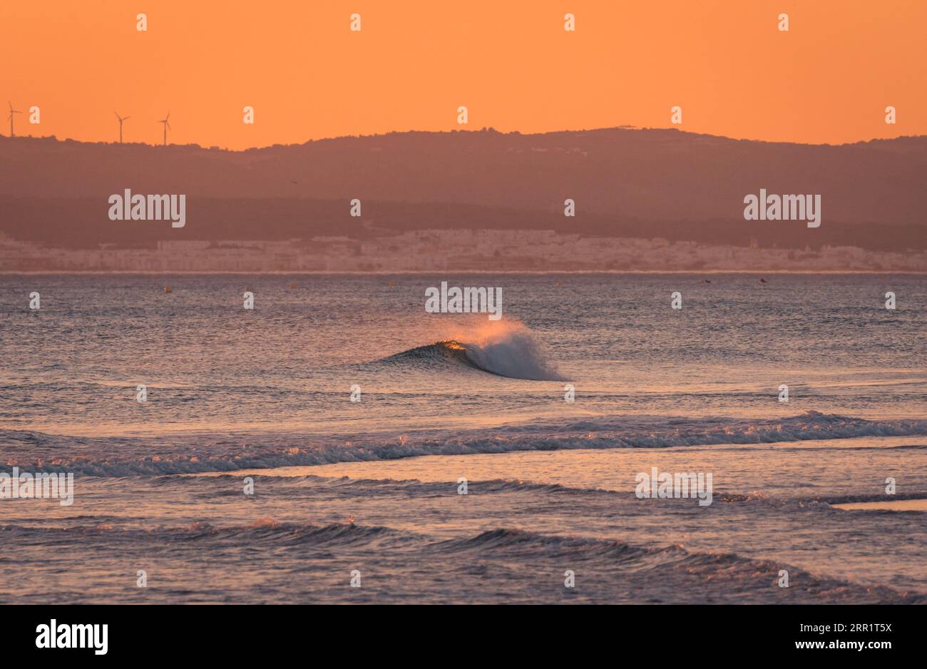 Vista mozzafiato del vibrante cielo al tramonto sul mare ondulato in serata Foto Stock