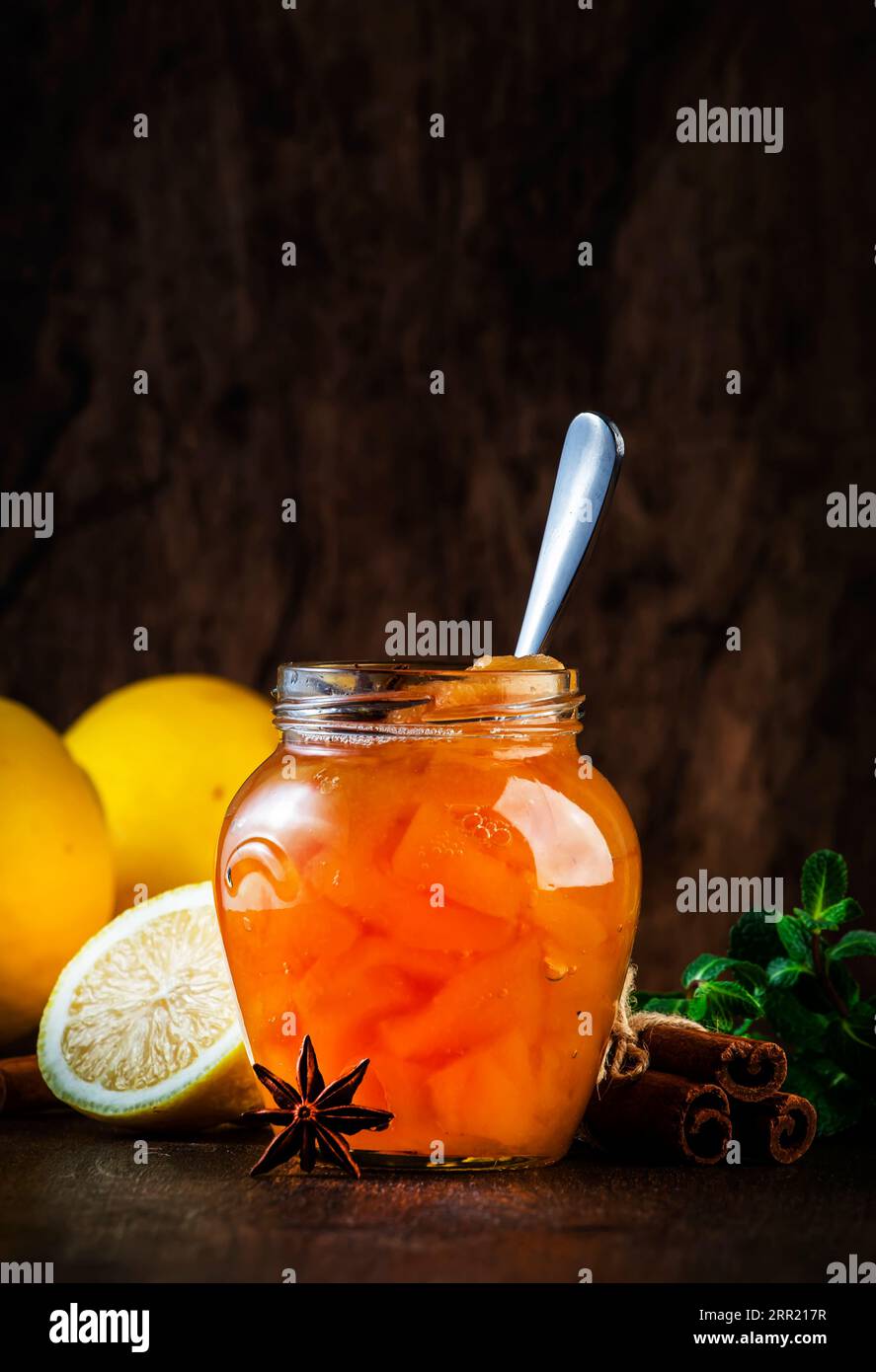 Marmellata di quince autunnale o confiture in vaso di vetro con cannella, succo di limone e anice su fondo rustico di legno Foto Stock