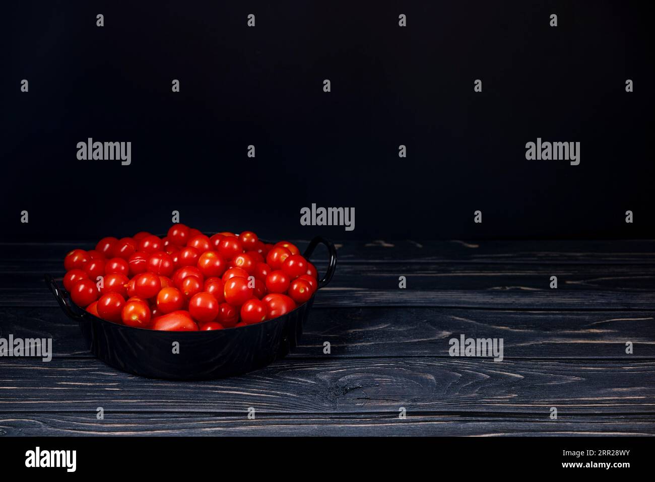 Cocktail di pomodori in pentola nera su legno, stanza per le copie, scuro Foto Stock