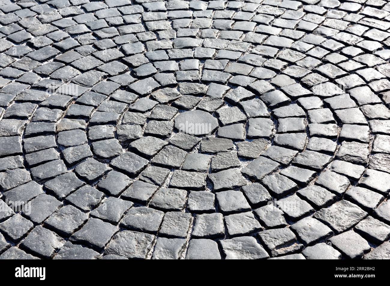 Sfondo di un vecchio primo piano di pavimentazione acciottolata. Pavimentazione in pietra prospettica, struttura di strada acciottolata, sfondo di strada acciottolata grigia. Foto Stock