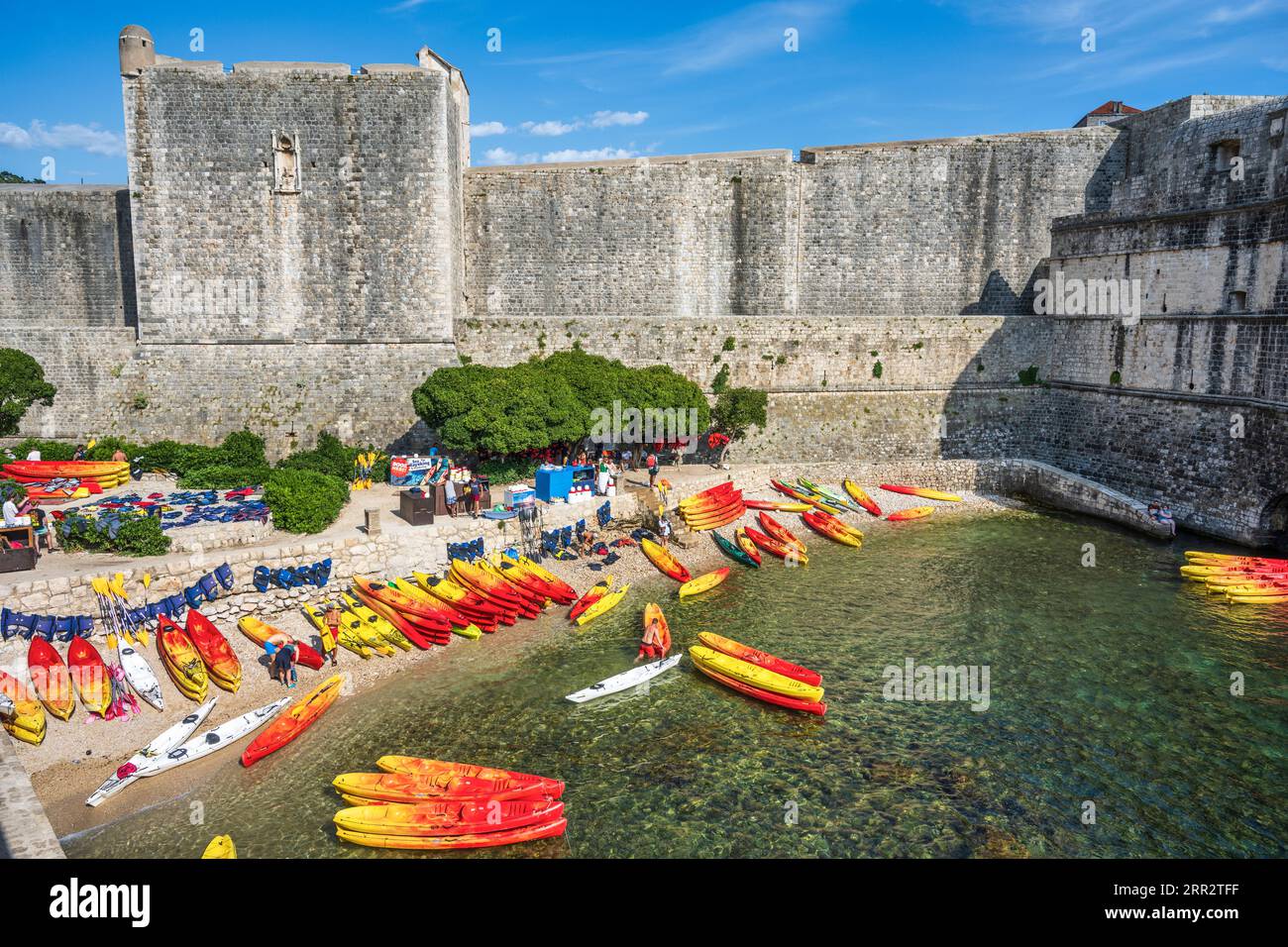 Le canoe si allineano sulla spiaggia sabbiosa di Kolorina Bay, il porto occidentale dell'antica città fortificata di Dubrovnik sulla costa dalmata della Croazia Foto Stock