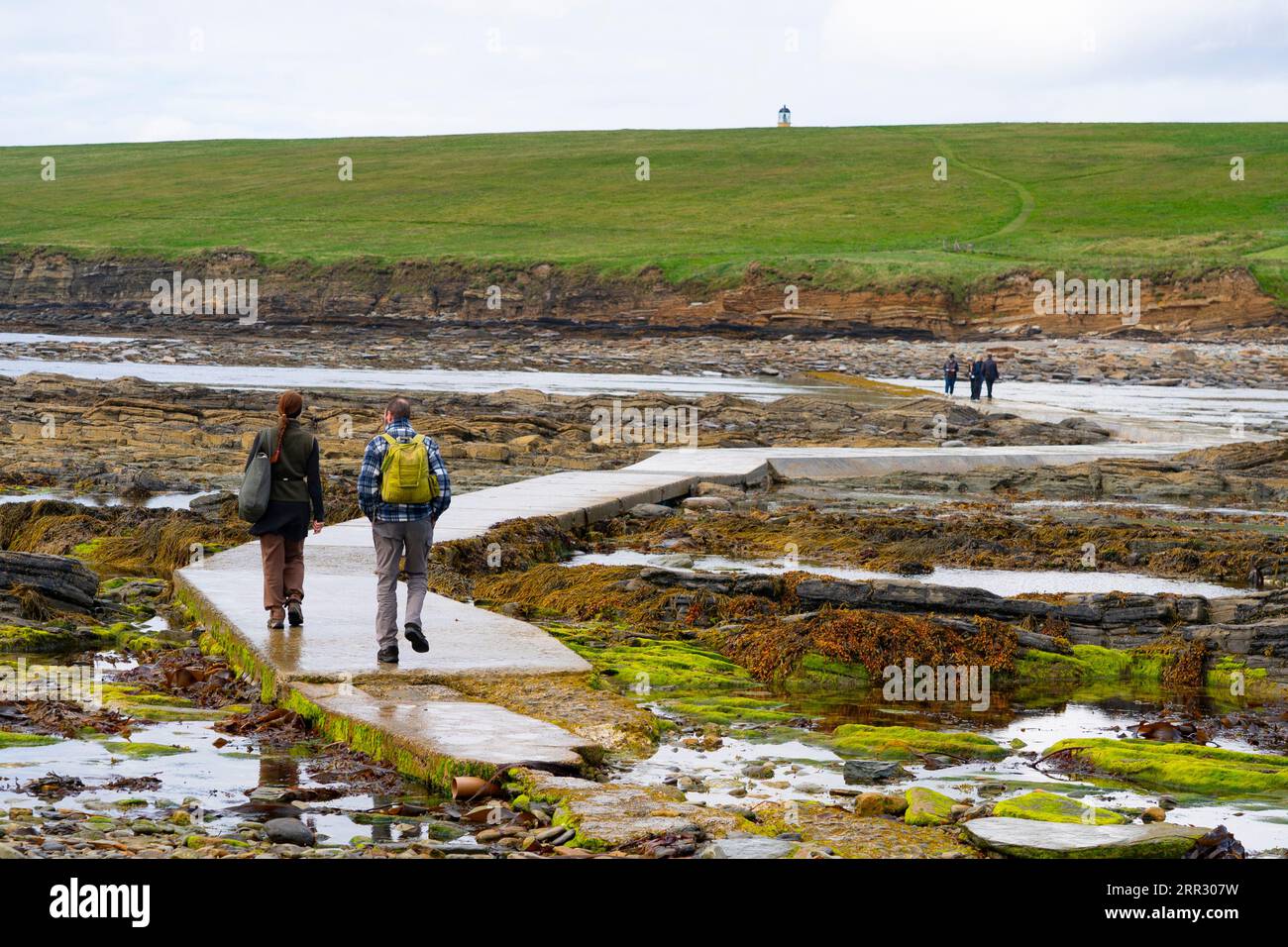 I visitatori camminano attraverso la strada rialzata delle maree fino all'isola Brough of Birsay nella terraferma occidentale, nelle isole Orcadi, in Scozia e nel Regno Unito. Foto Stock