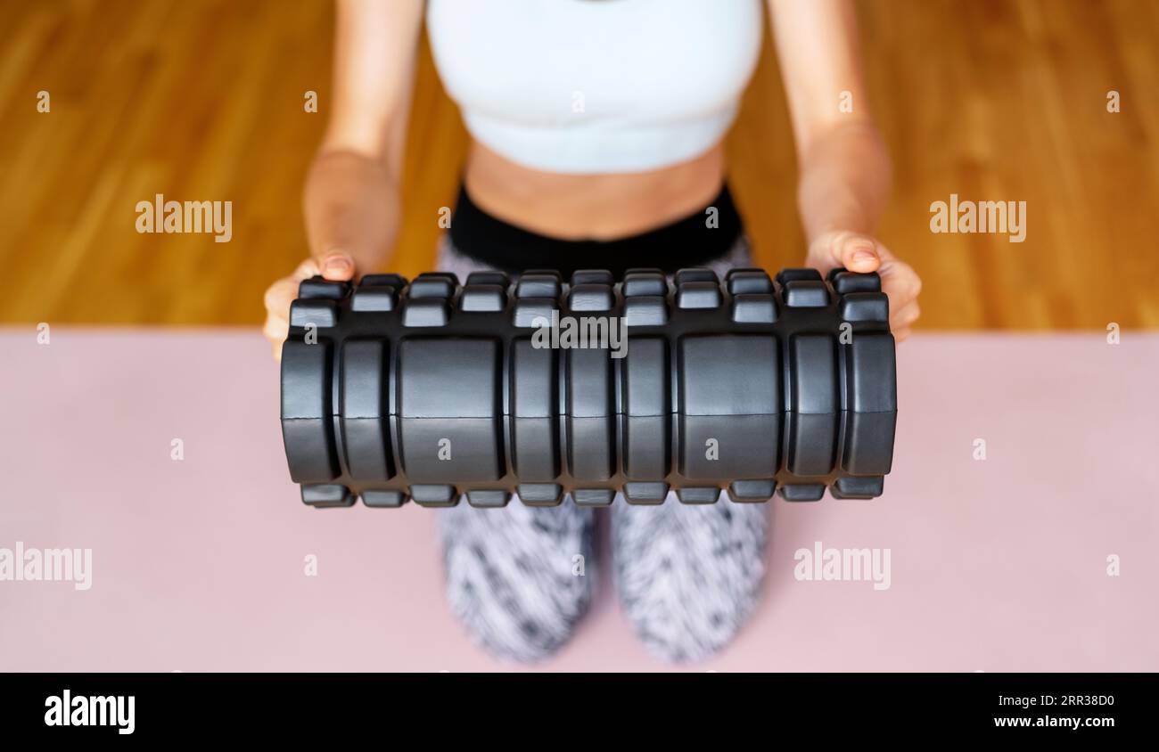 Rullo in schiuma nera con mani, donna sportiva. Foto Stock