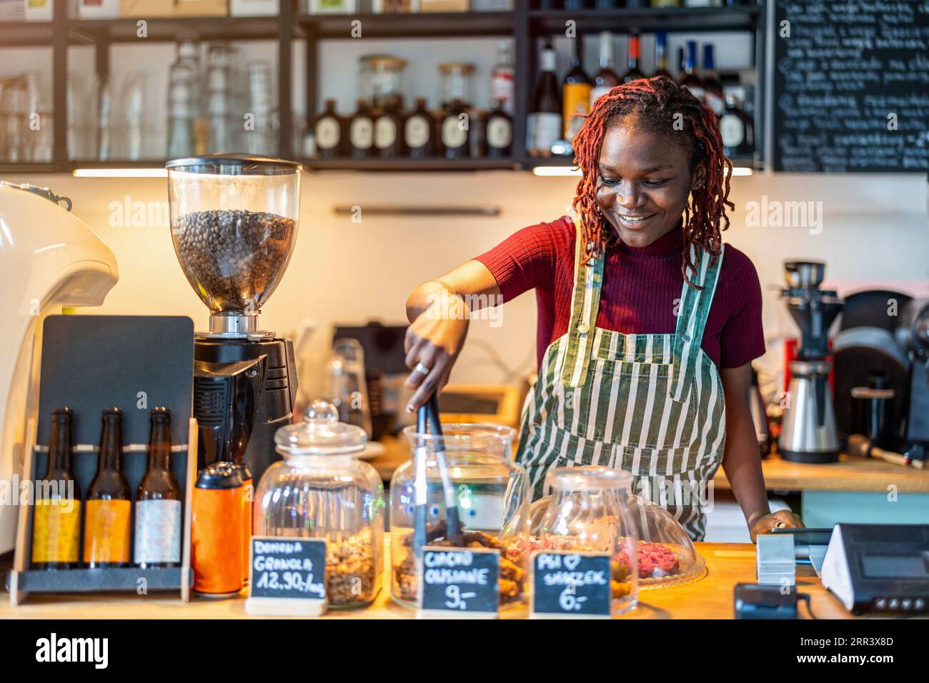 Ritratto di un barista genderqueer che prepara il caffè al bancone della caffetteria Foto Stock