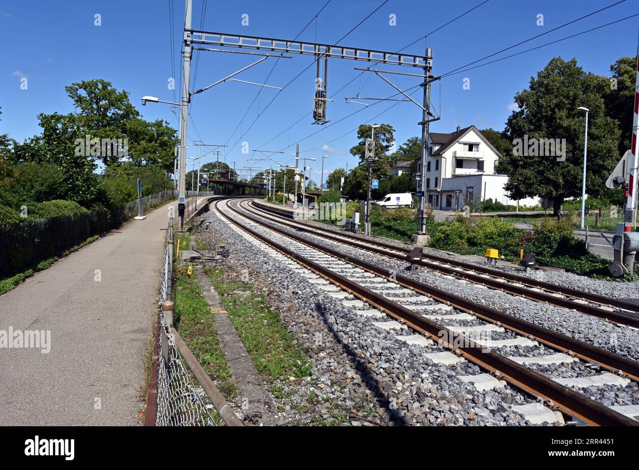 I binari o i binari che conducono alla stazione ferroviaria con edifici nel villaggio di Urdorf in Svizzera. Foto Stock