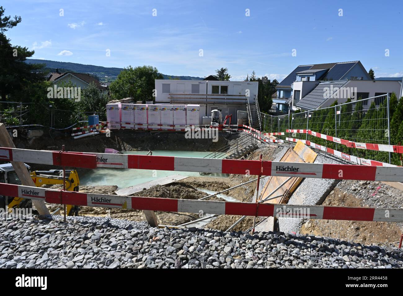 Cantiere e fossa scavata per la fondazione della casa recintata con barriere rosse e bianche. Foto Stock