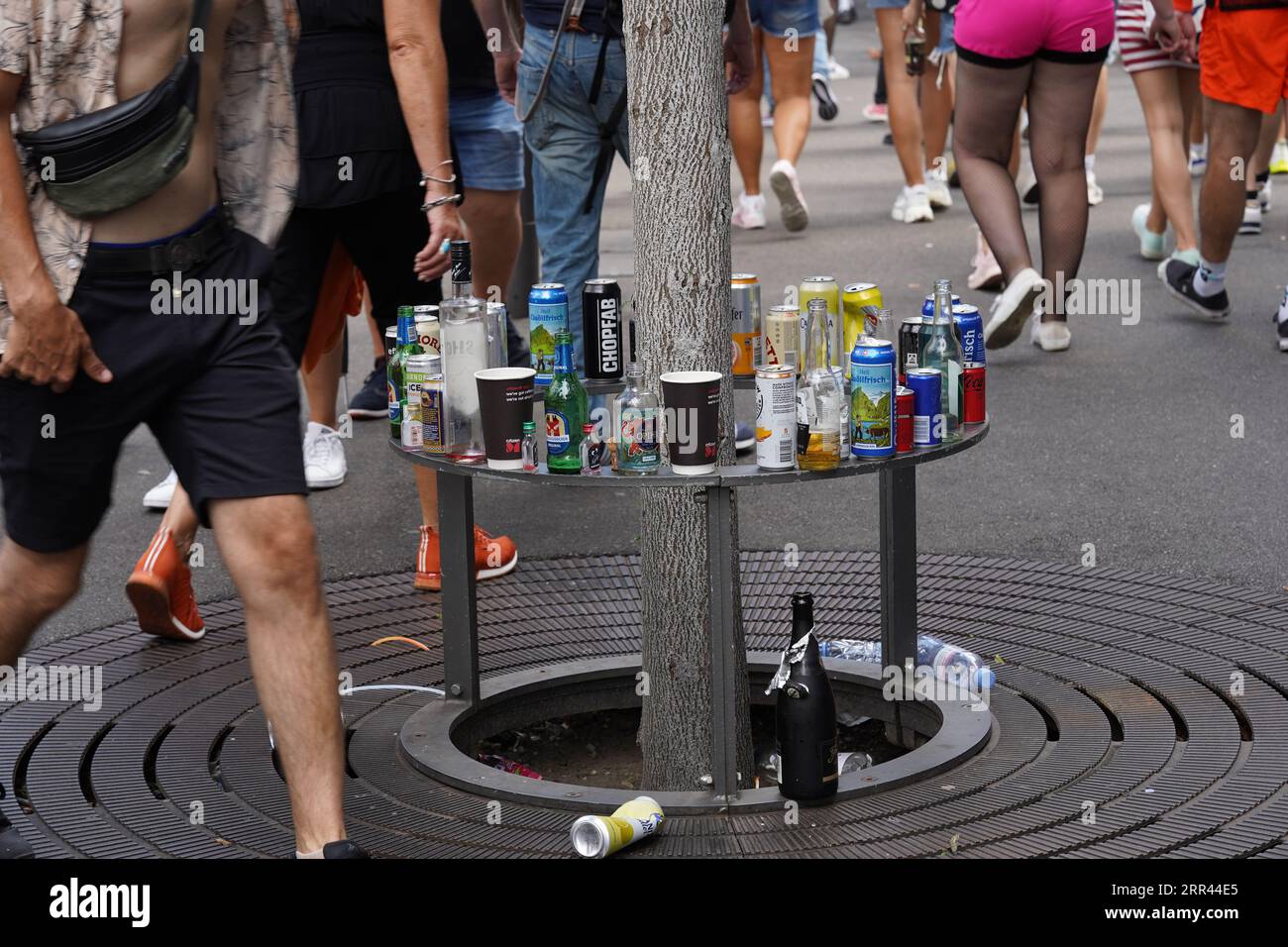 Bottiglie vuote e rifiuti alimentari messi sulla protezione metallica dell'albero in strada. Foto Stock