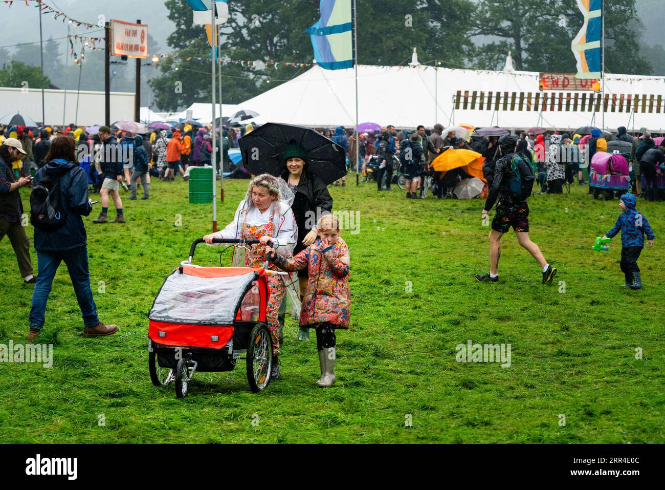 Una famiglia con una carrozzina nella pioggia e nel fango. Green Man Festival, Brecon, Galles, Regno Unito, 2023. Foto: Rob Watkins Foto Stock