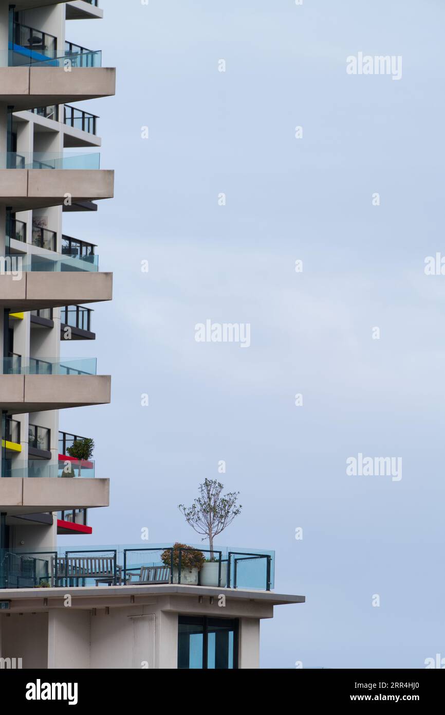 Stile di vita degli appartamenti a Melbourne, Australia, che mostra l'esterno dell'edificio, balconi e ringhiere di vetro con un debole cielo blu. Foto Stock
