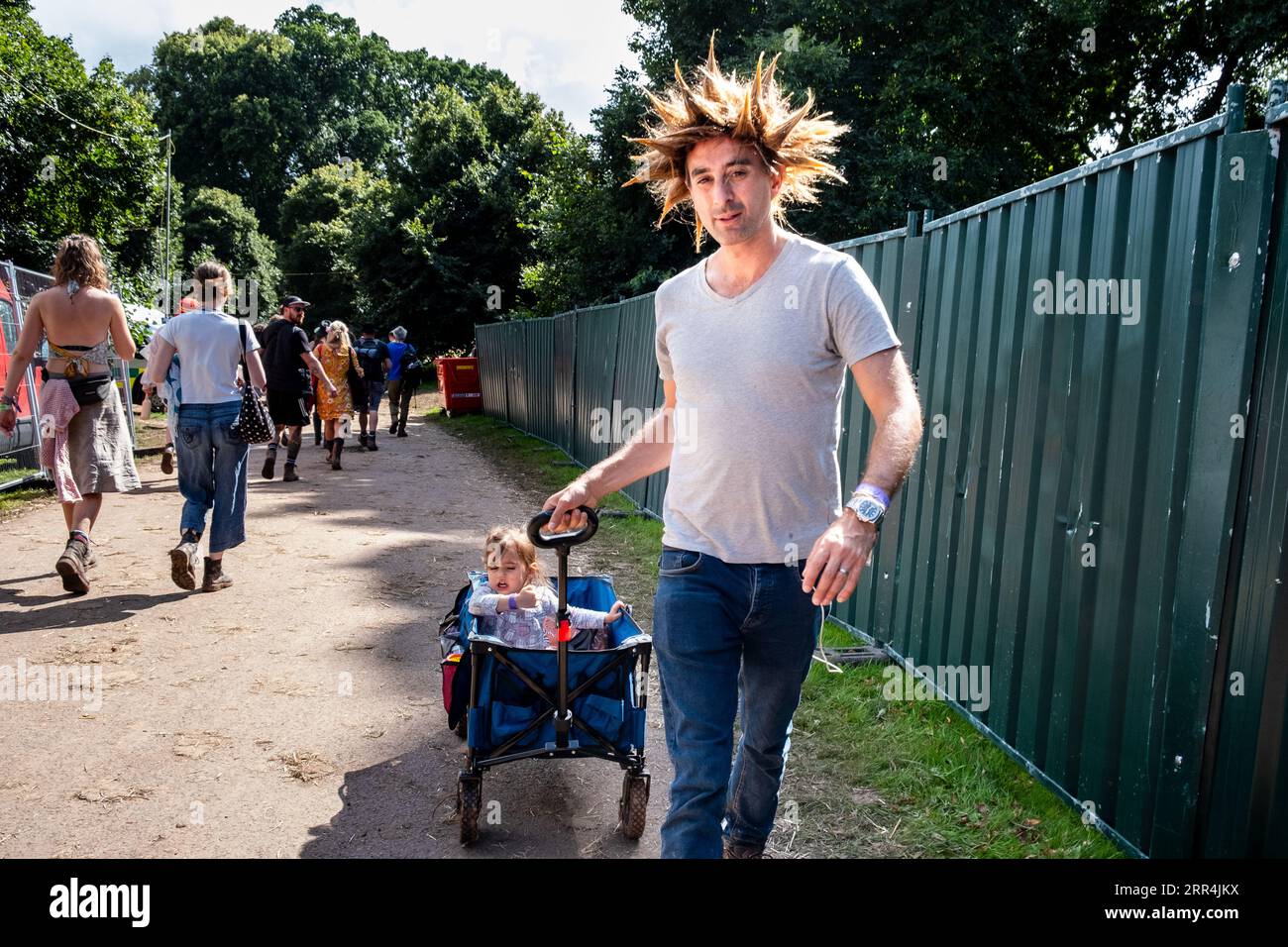Un padre dai capelli spiky mohawk tira una carrozza trolley al Green Man Festival, Brecon, Galles, Regno Unito, 2023. Foto: Rob Watkins Foto Stock