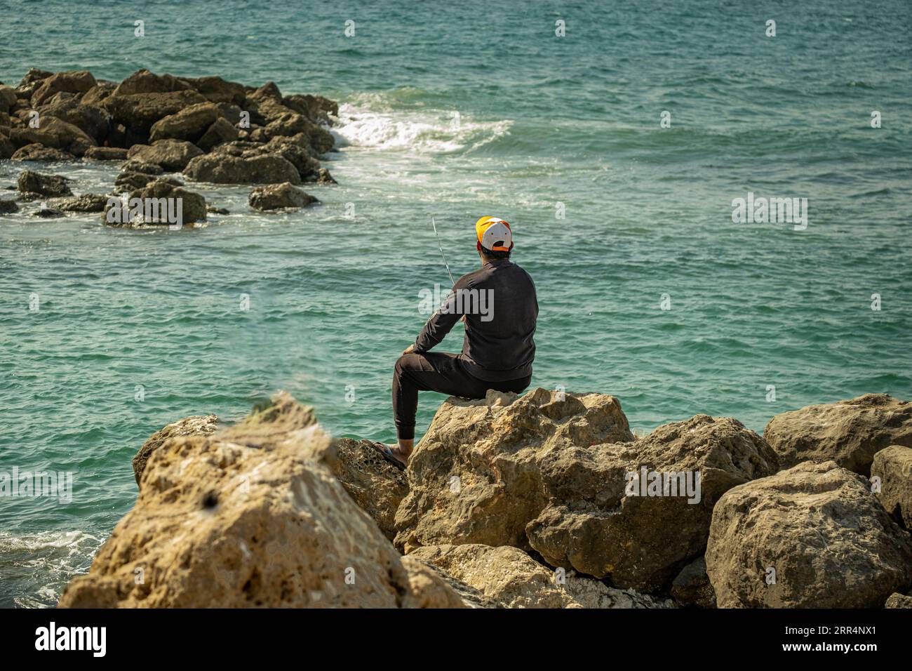 La ricerca della pesca da parte del viaggiatore in questo pittoresco sfondo è una testimonianza dei piaceri semplici e sereni che la natura ci conferisce, Oman Foto Stock