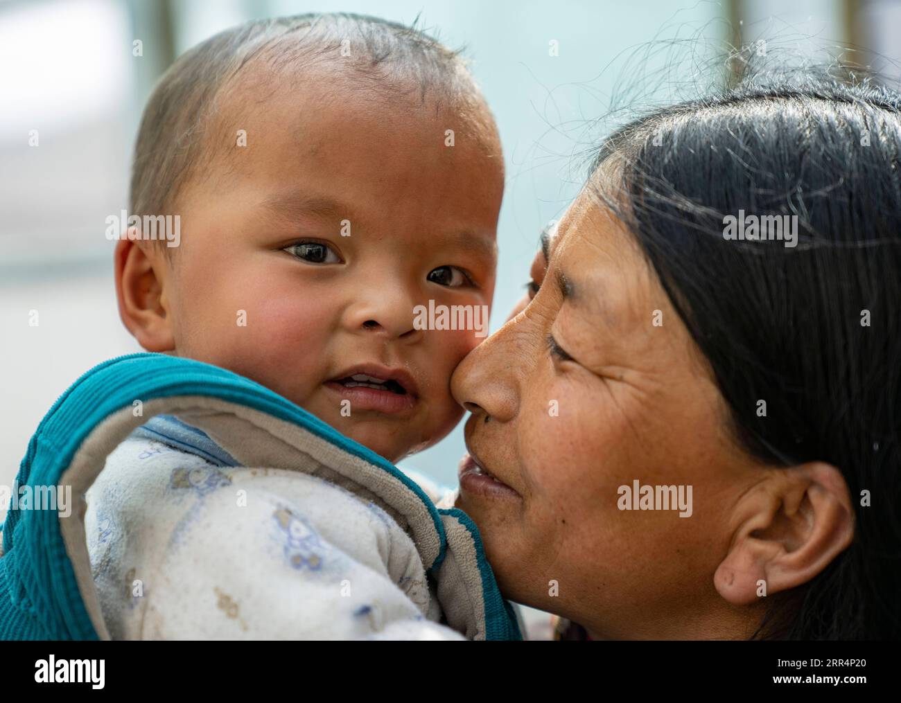 201210 -- LHASA, 10 dicembre 2020 -- Un abitante del villaggio interagisce con un bambino nel comune di Pumaqangtang della contea di Nagarze nello Shannan, regione autonoma del Tibet nel sud-ovest della Cina, 15 aprile 2020. Pumaqangtang, la città più alta della Cina, ha un'altitudine media di 5.373 metri, con livelli di ossigeno inferiori al 40% a livello del mare. Gli abitanti del villaggio vivevano in case di roccia senza elettricità, acqua corrente, verdura o frutta disponibili. Tali condizioni di vita duri continuarono fino agli anni '1970 Al giorno d'oggi, tutti gli abitanti del villaggio di Pumaqangtang si sono trasferiti in residenze migliori. Rispetto al passato, il Foto Stock