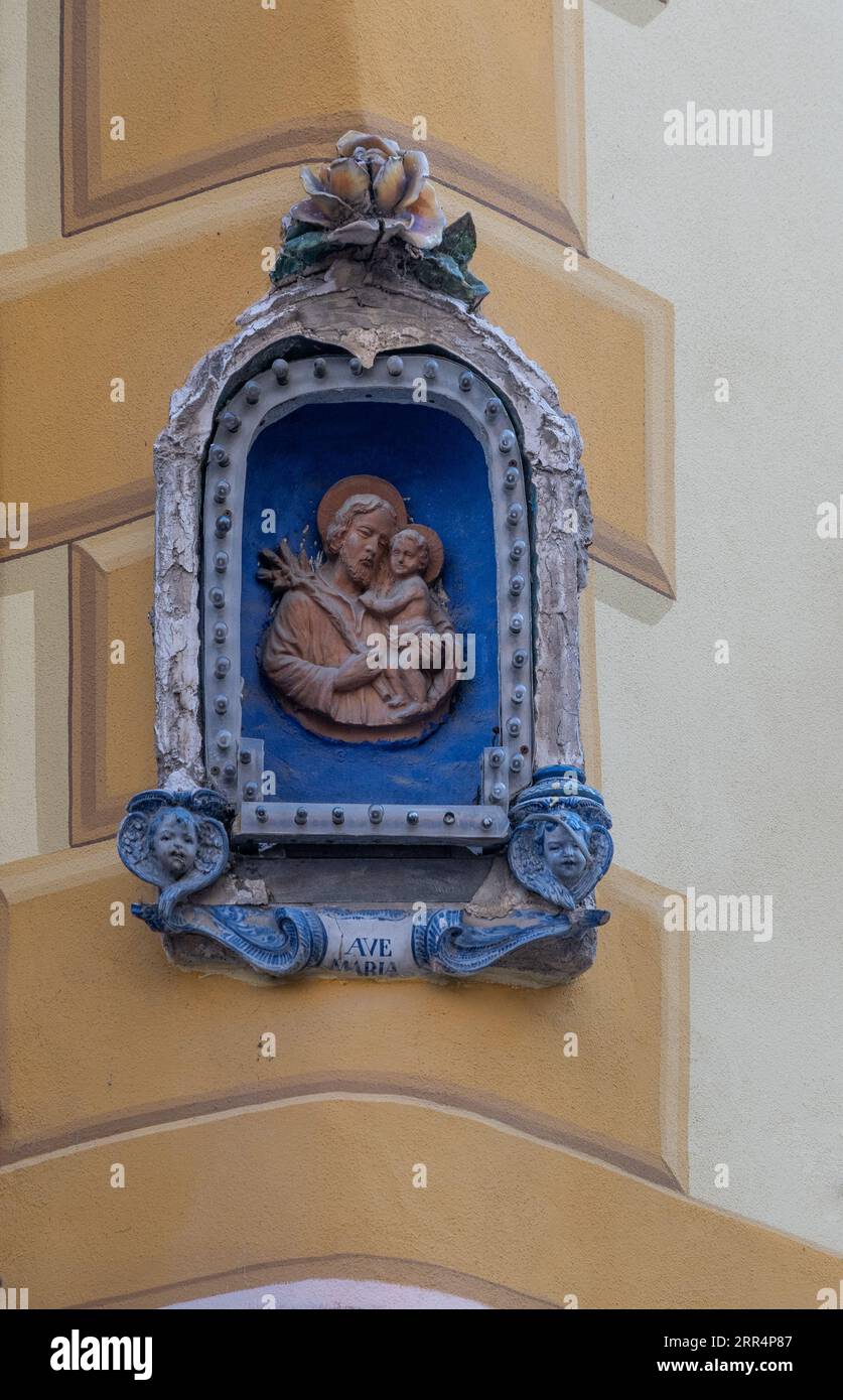 Santuario votivo in ceramica raffigurante San Giuseppe con Gesù bambino in un angolo di un edificio nel centro storico, Albissola Marina, Savona, Liguria, Italia Foto Stock