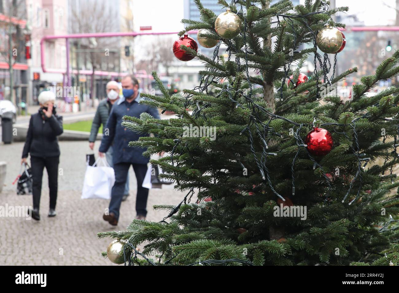 201216 -- BERLINO, 16 dicembre 2020 -- i pedoni camminano davanti a un albero di Natale a Berlino, capitale della Germania, 16 dicembre 2020. La Germania entrerà in un blocco più severo da mercoledì, chiudendo negozi non essenziali e limitando le dimensioni degli incontri privati, il Cancelliere Angela Merkel e i leader regionali hanno concordato domenica. Secondo un documento politico, le misure restrittive più severe, che saranno efficaci fino al 10 gennaio, sono state in risposta a una crescita esponenziale del numero di casi di COVID-19 in Germania. ShanYuqi GERMANY-BERLIN-COVID-19-LOCKDOWN ShanxYuqi PUBLICATIONxNOTxINxCHN Foto Stock