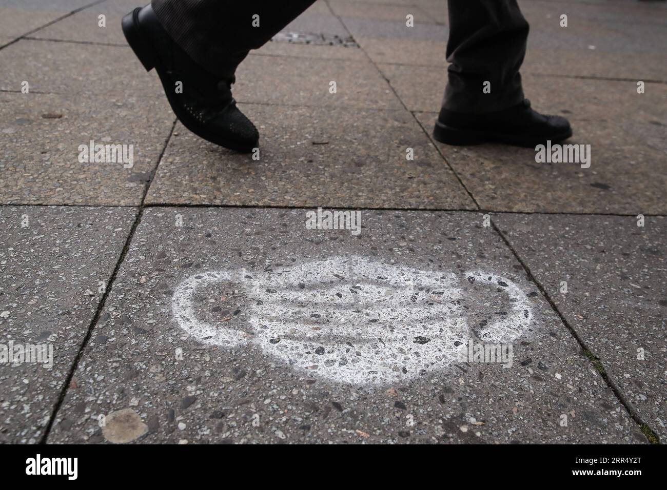 201216 -- BERLINO, 16 dicembre 2020 -- Un pedone passeggia davanti a una maschera disegnata per terra a Berlino, capitale della Germania, 16 dicembre 2020. La Germania entrerà in un blocco più severo da mercoledì, chiudendo negozi non essenziali e limitando le dimensioni degli incontri privati, il Cancelliere Angela Merkel e i leader regionali hanno concordato domenica. Secondo un documento politico, le misure restrittive più severe, che saranno efficaci fino al 10 gennaio, sono state in risposta a una crescita esponenziale del numero di casi di COVID-19 in Germania. ShanYuqi GERMANY-BERLIN-COVID-19-LOCKDOWN ShanxYuqi PUBLICATIONxNOTxINxCHN Foto Stock