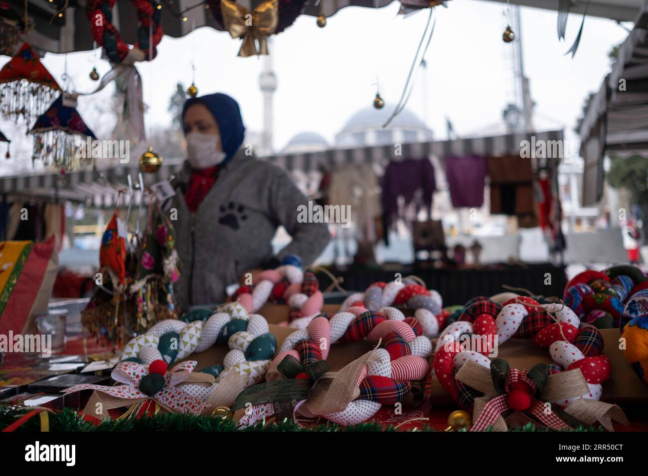 201217 -- ISTANBUL, 17 dicembre 2020 -- Una donna vende oggetti d'artigianato in un bazar a Istanbul, Turchia, il 17 dicembre 2020. Il bazar presso un molo nel quartiere Besiktas di Istanbul è pieno di saponi fatti a mano, giocattoli, pezzi a maglia, oggetti in porcellana e gioielli, tutti prodotti a casa da donne locali. Nell'ambito di un progetto avviato per sostenere l'imprenditorialità femminile, circa 500 donne hanno recentemente iniziato a vendere i loro prodotti al bazar che è stato dato il via lunedì. Foto di /Xinhua TO GO WITH Feature: Il programma imprenditoriale aiuta le donne turche a vendere prodotti fatti in casa TURCHIA-ISTANBUL-WOMEN ENTREPRENEURSHIP OsmanxOr Foto Stock