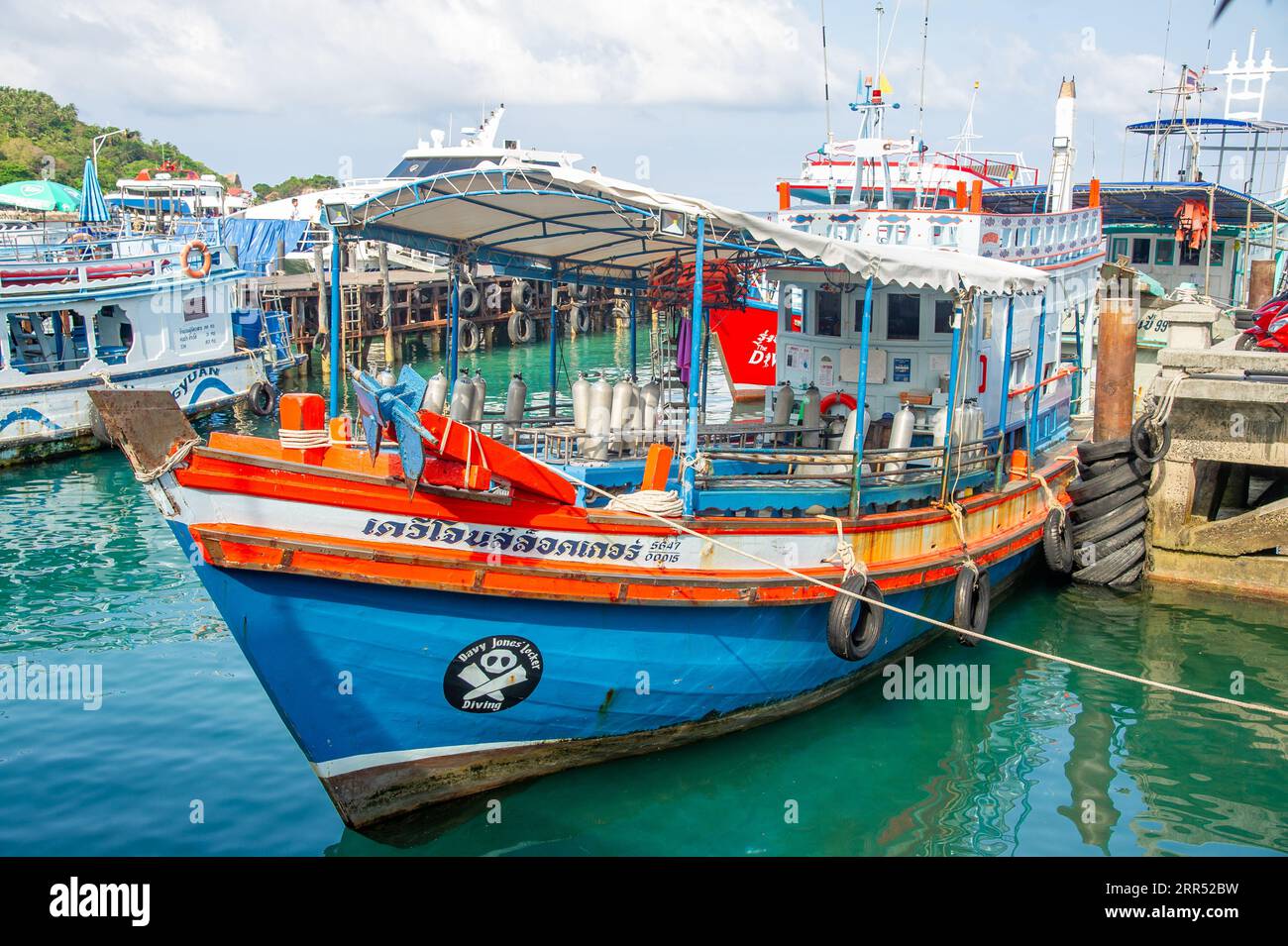 21 marzo 2023 - Ko Tao Thailandia - barca dai colori vivaci di arancione e blu, piena di tubi per immersioni ad ossigeno attende i turisti. Foto Stock