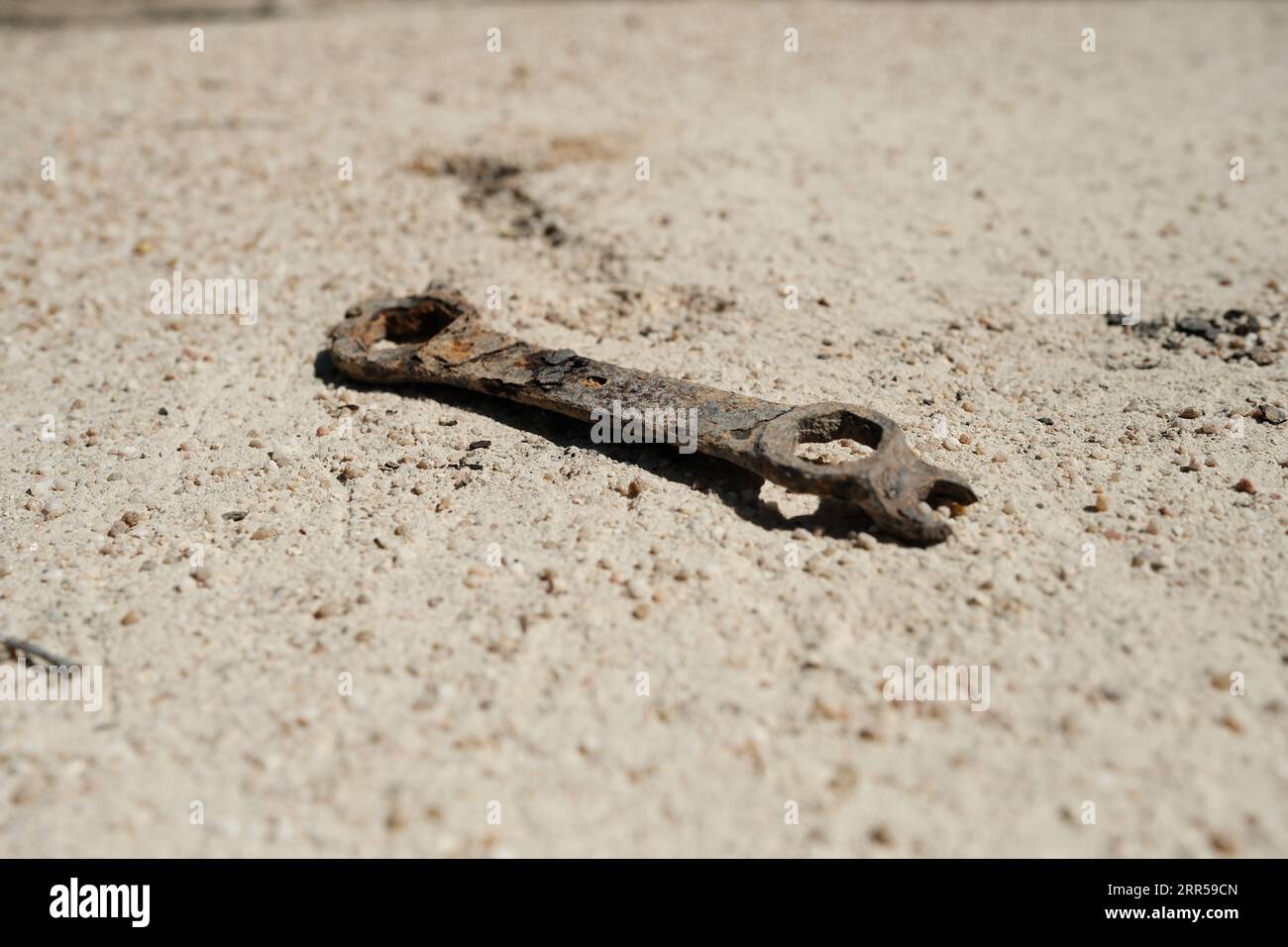 Una vecchia chiave arrugginita che giace sul terreno sabbioso Foto Stock