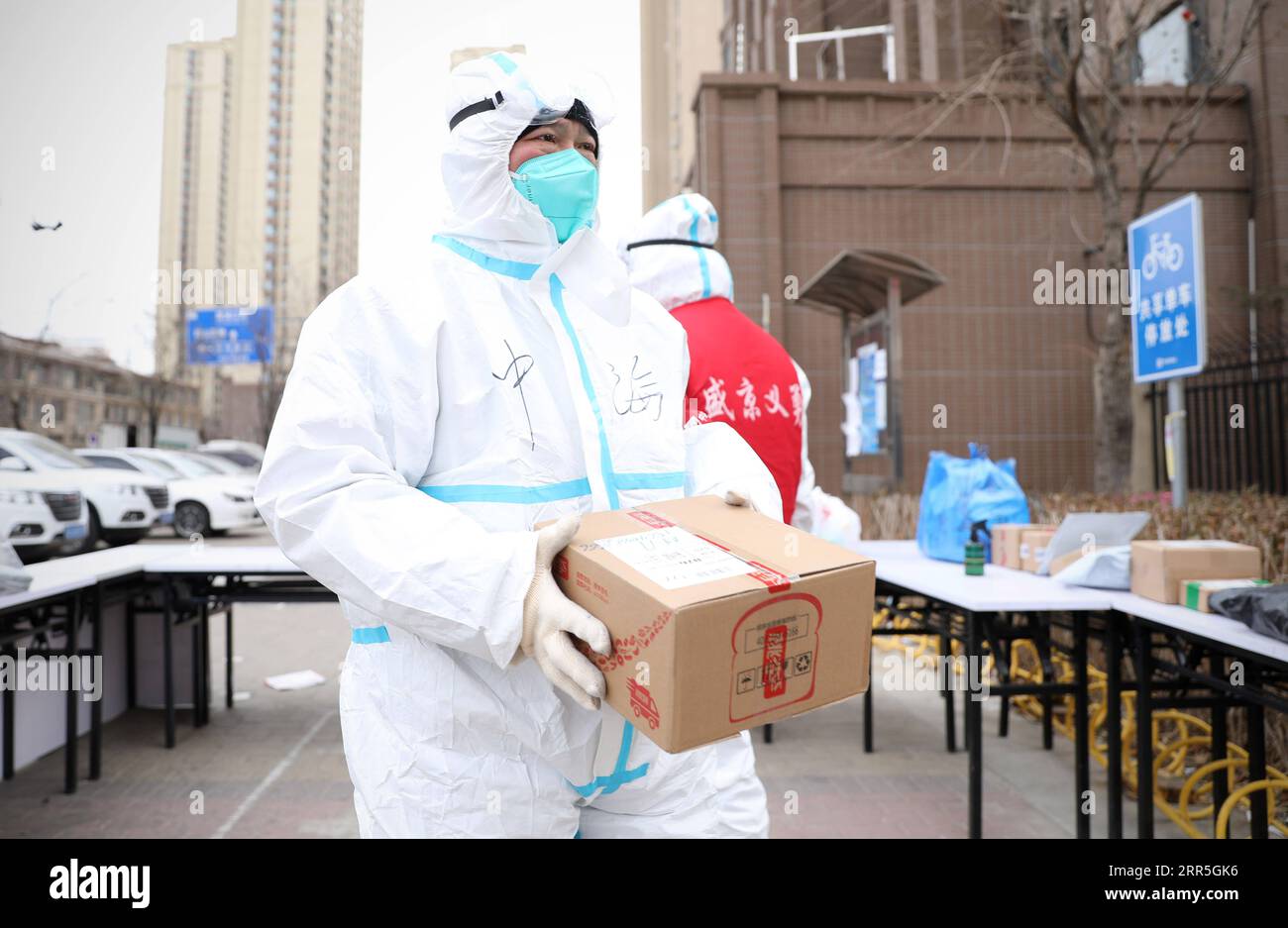 210107 -- SHENYANG, 7 gennaio 2021 -- Un membro dello staff della prevenzione e del controllo delle epidemie fornisce provviste in un complesso residenziale, identificato come zona a medio rischio per COVID-19, nel distretto di Huanggu a Shenyang, nella provincia di Liaoning della Cina nordorientale, 6 gennaio 2021. Shenyang sta vivendo una forte ondata di freddo che è iniziata mercoledì, quando la temperatura è scesa vicino a meno 20 gradi Celsius. CHINA-LIAONING-SHENYANG-COLD WAVECN YaoxJianfeng PUBLICATIONxNOTxINxCHN Foto Stock