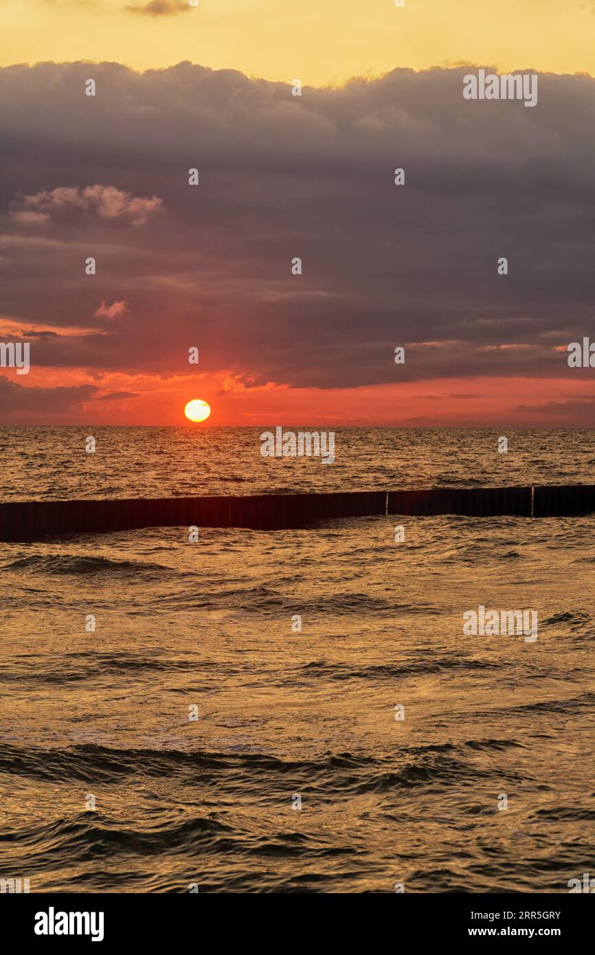 Vista sul mare al tramonto con il tempo tempestoso. Onde sul mare e nuvole scure nel cielo. Mar Baltico, Pomerania occidentale, Polonia, Europa. Foto Stock