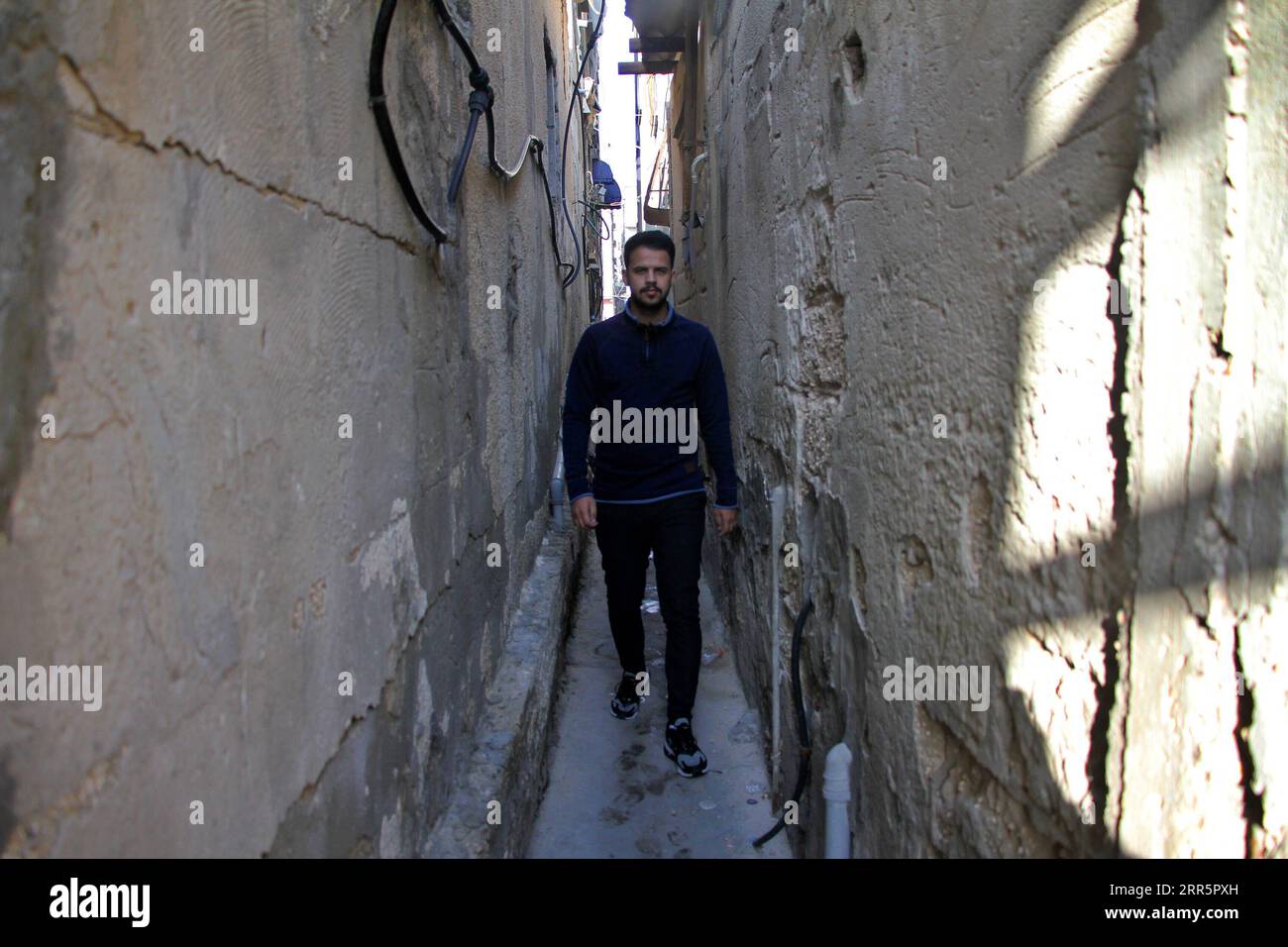 210113 -- GAZA, 13 gennaio 2021 -- Un uomo cammina in un vicolo al campo profughi di al-Shati nella città di Gaza, 11 gennaio 2021. Il 24 agosto 2020, le autorità di Gaza gestite da Hamas hanno annunciato i primi quattro casi di COVID-19 e hanno imposto una serie di misure restrittive per limitare la diffusione del virus. Da allora, tutte le chiese, le moschee, le scuole, i mercati e le istituzioni private sono stati chiusi e gli incontri pubblici sono vietati. PER ANDARE CON la funzione: Gli studenti palestinesi rifugiati sperano in una piena istruzione nell'era post-pandemia foto di Rizek Abdeljawad/Xinhua MIDEAST-GAZA-RIFUGIATO xiongsihao PUBLICATIONxNOTxINxCHN Foto Stock