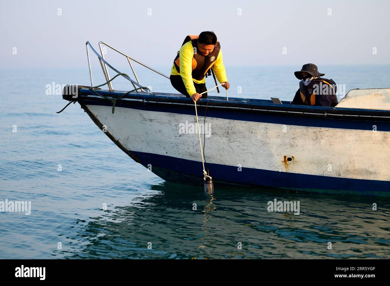 210119 -- BEIHAI, 19 gennaio 2021 -- Chen Mo, ricercatore associato dell'Accademia delle Scienze del Guangxi e membro del team di ricerca, mette un analizzatore della qualità dell'acqua nell'acqua nel Golfo di Beibu, nella regione autonoma del Guangxi Zhuang della Cina meridionale, 15 gennaio 2021. La balena di Bryde, vista principalmente nelle acque tropicali e subtropicali, è considerata una specie molto misteriosa di cetacei, con una lunghezza corporea compresa tra 10 e 12 metri e un peso fino a 15 tonnellate. Un team di ricerca scientifica, composto da scienziati, videografi, pescatori e volontari, ha condotto ricerche sulle balene e ha assunto il ruolo Foto Stock