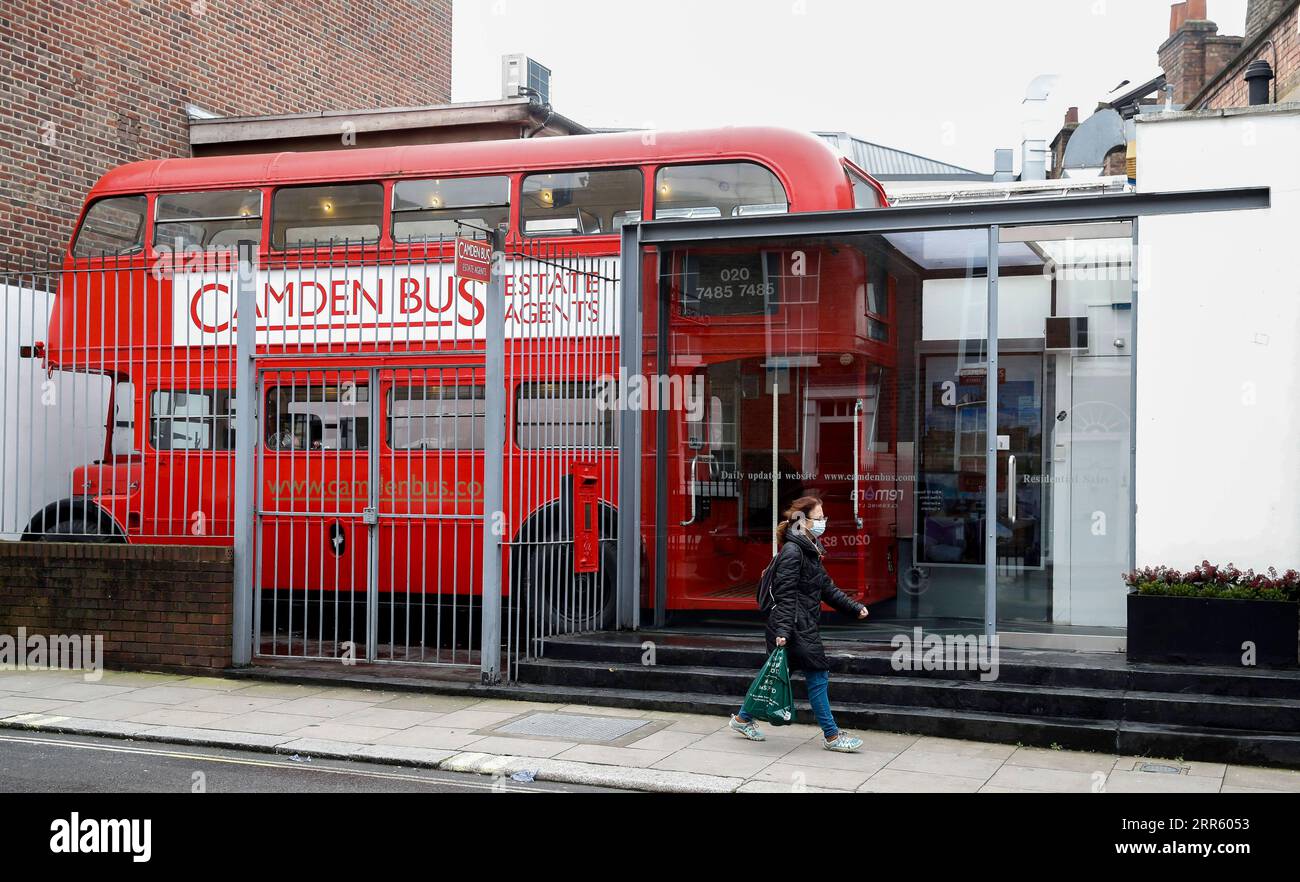 210120 -- LONDRA, 20 gennaio 2021 -- Una donna che indossa una maschera cammina davanti a un agente immobiliare sotto forma di un autobus rosso a due piani a Londra, in Gran Bretagna, il 19 gennaio 2021. Il numero di persone che sono morte entro 28 giorni da un test positivo per il coronavirus ha superato il triste traguardo di 90.000 in Gran Bretagna dopo che altri 1.610 sono stati confermati, secondo i dati ufficiali pubblicati martedì. L'ultimo bilancio giornaliero di morti, il più alto dall'inizio della pandemia nel paese, ha portato il numero totale di decessi correlati al coronavirus in Gran Bretagna a 91.470, i dati hanno mostrato. REGNO UNITO-LONDRA-COVID-19-NUMERO DI MORTI HANXY Foto Stock