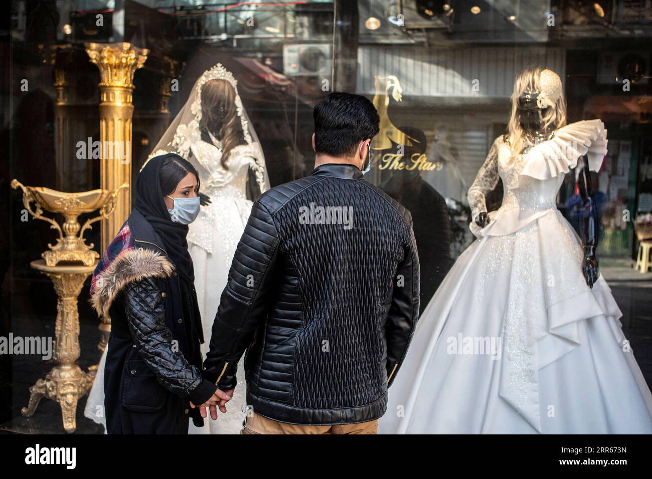 210128 -- TEHERAN, 28 gennaio 2021 -- la gente guarda la vetrina di un negozio di abiti da sposa a Teheran, Iran, il 28 gennaio 2021. Per molti iraniani che cercano di legare il nodo, sono stati costretti ad apportare modifiche e adeguamenti ai loro piani di matrimonio, affrontando gli ostacoli causati dalla pandemia di COVID-19. Foto di /Xinhua IRAN-TEHERAN-COVID-19-WEDDING PLAN-CHANGE AhmadxHalabisaz PUBLICATIONxNOTxINxCHN Foto Stock