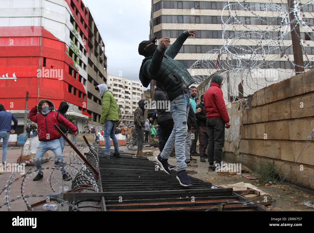 210128 -- TRIPOLI, 28 gennaio 2021 -- la gente lancia pietre all'edificio del governo del governatorato durante una protesta a Tripoli, in Libano, il 28 gennaio 2021. Giovedì a Tripoli è scoppiata una nuova serie di scontri tra forze di sicurezza e manifestanti contro il blocco totale imposto dalle autorità per frenare la COVID-19, hanno riferito i media locali. Foto di Khaled/Xinhua LEBANON-TRIPOLI-COVID-19-LOCKDOWN-PROTEST LiuxZongya PUBLICATIONxNOTxINxCHN Foto Stock