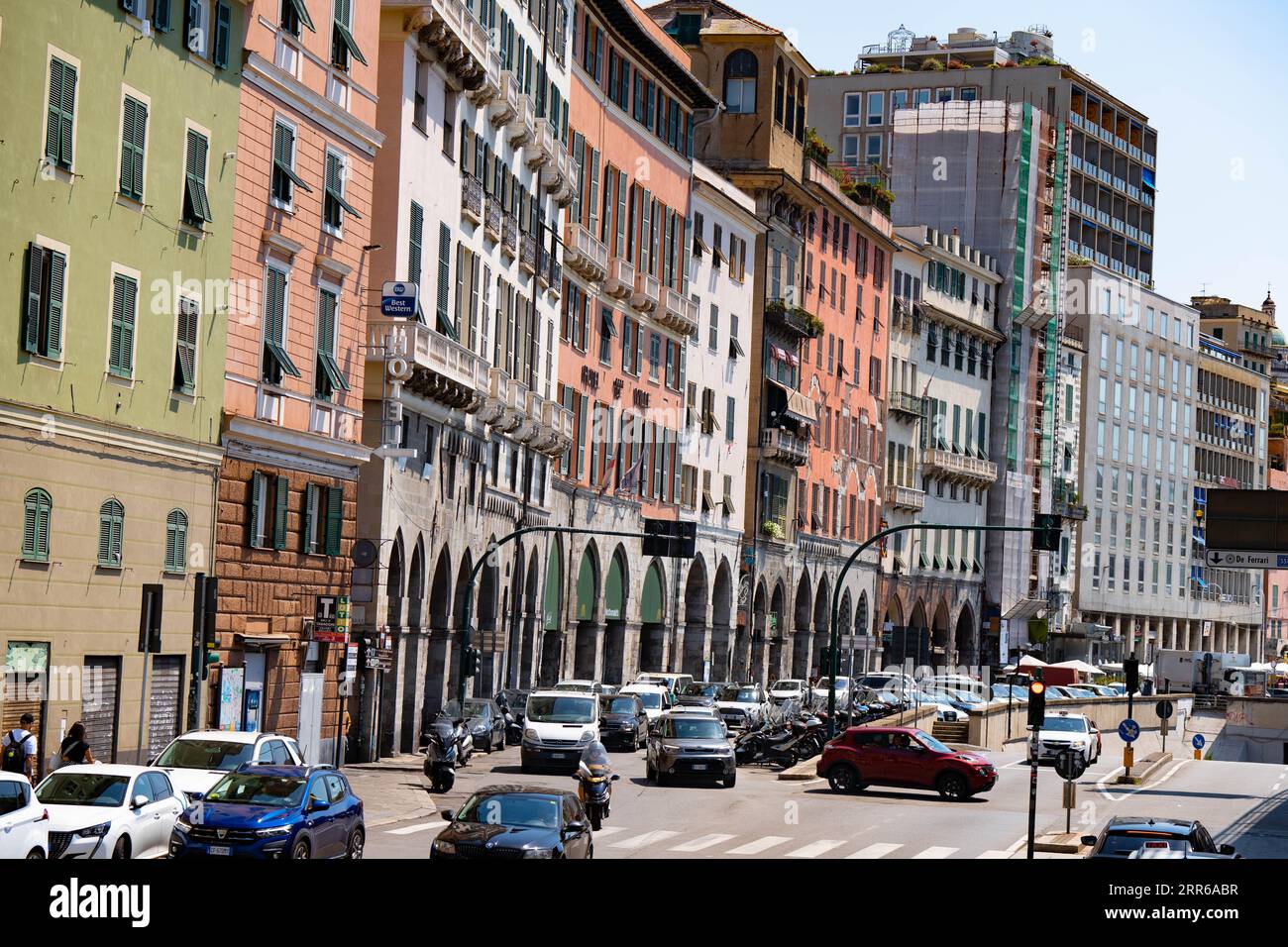 Vita in un trafficato incrocio di Genova in Italia in una calda mattinata di agosto con appartamenti colorati che adornano la strada. Una bellissima fotografia a colori della vita Foto Stock