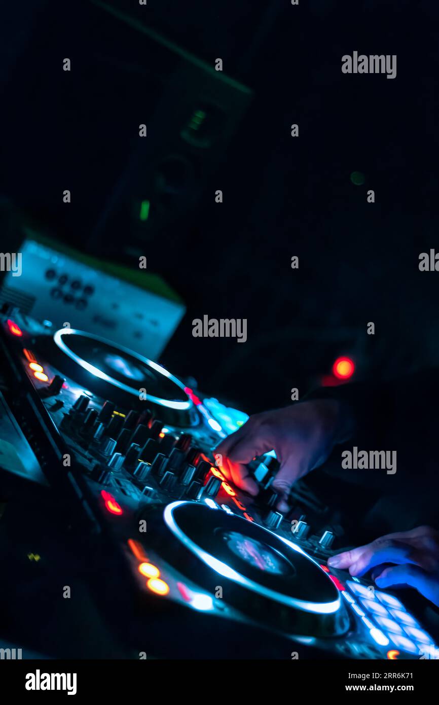 Primo piano delle mani dei DJ che suonano vari controlli dei brani sulla console di mixaggio dei DJ durante la festa del nightclub. Foto Stock