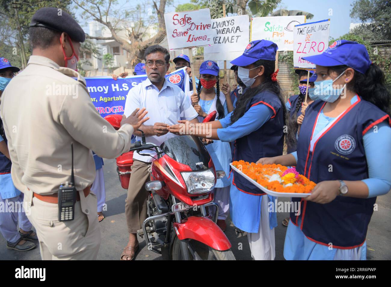 210225 -- AGARTALA, 25 febbraio 2021 -- i volontari danno fiori a un motociclista senza casco nell'ambito di un programma di sensibilizzazione sulla sicurezza stradale e le regole del traffico, alla periferia di Agartala, la capitale dello stato nord-orientale dell'India di Tripura, 25 febbraio 2021. Str/ INDIA-AGARTALA-PROGRAMMA DI SICUREZZA STRADALE Xinhua PUBLICATIONxNOTxINxCHN Foto Stock