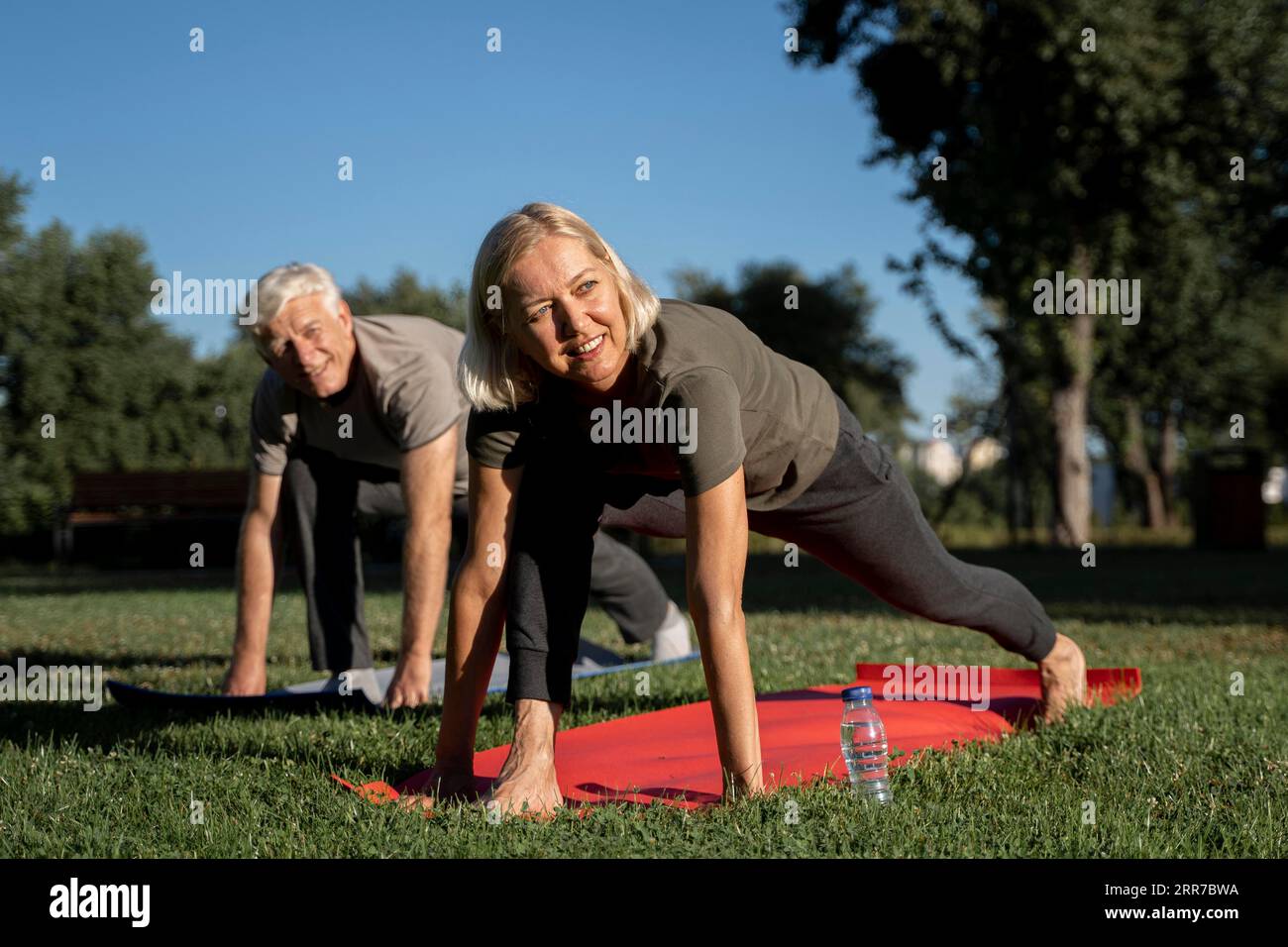 Una coppia di anziani sorridenti che pratica yoga all'aperto Foto Stock