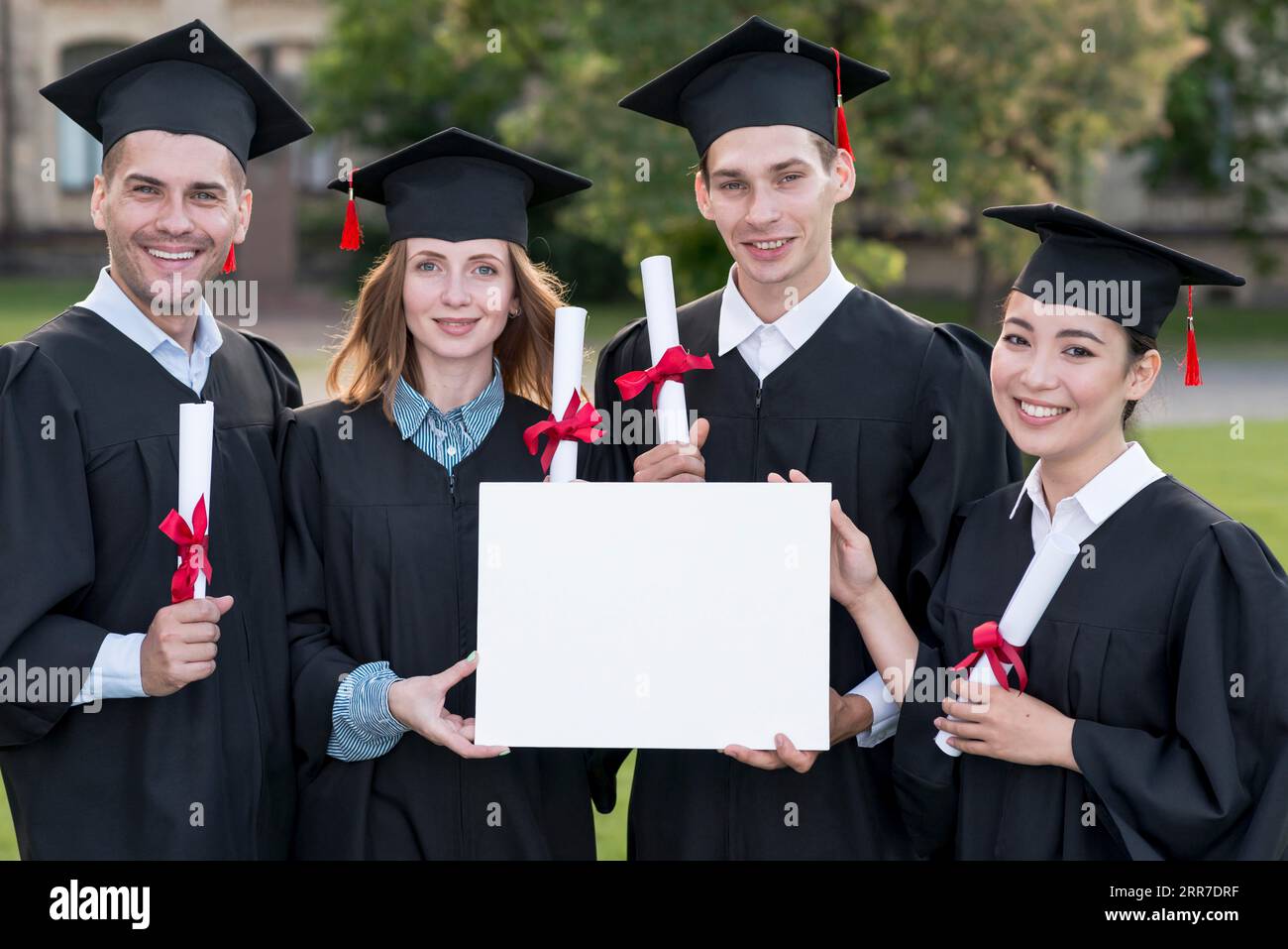 Concetto di laurea con gli studenti in possesso di un modello di certificato vuoto Foto Stock