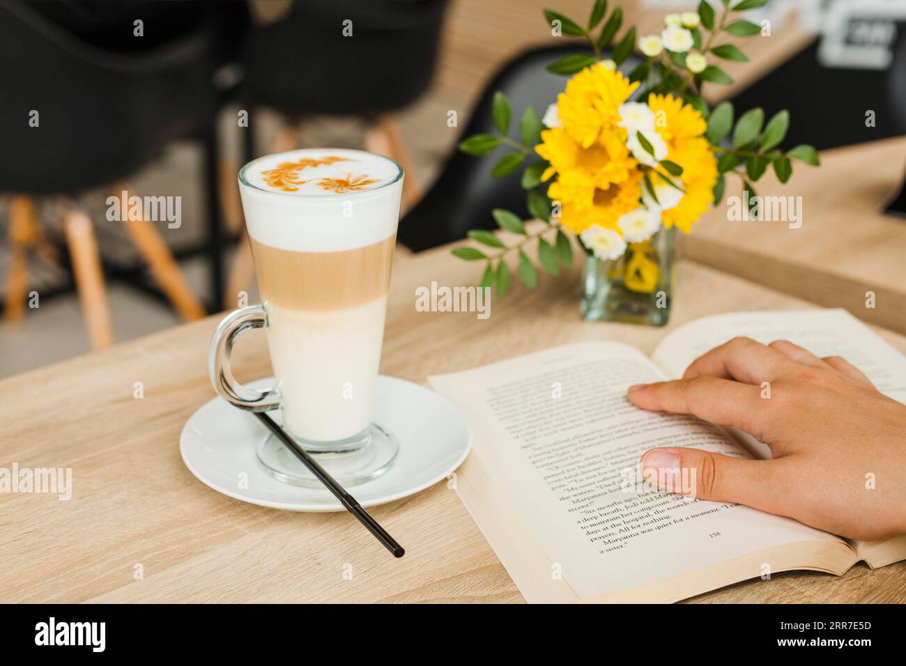 Persona che legge un libro vicino al caffè Foto Stock