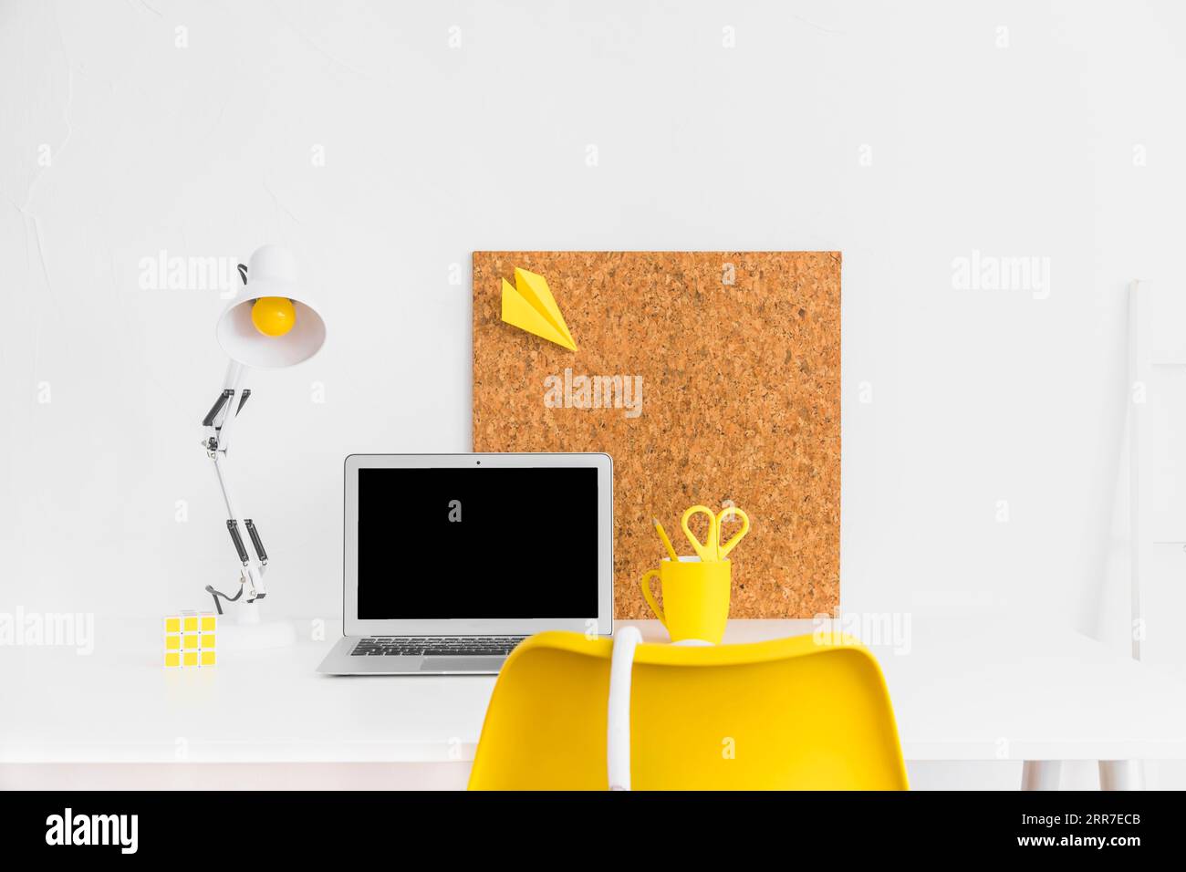 Elegante area di lavoro con colori giallo-bianco e tabellone in sughero Foto Stock