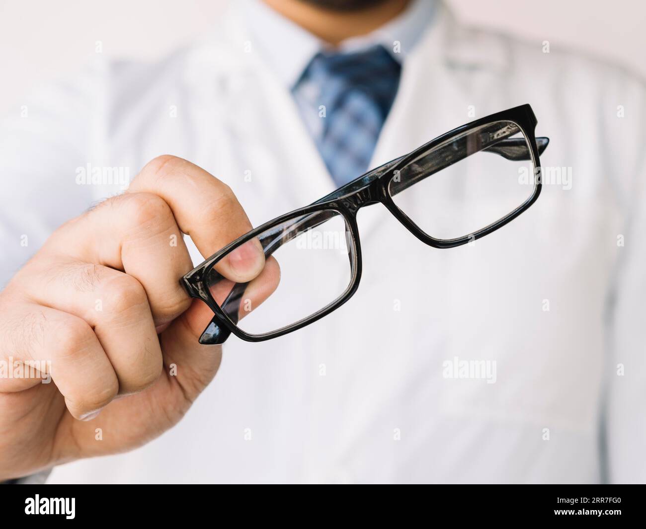 Medico che tiene un paio di occhiali neri Foto Stock