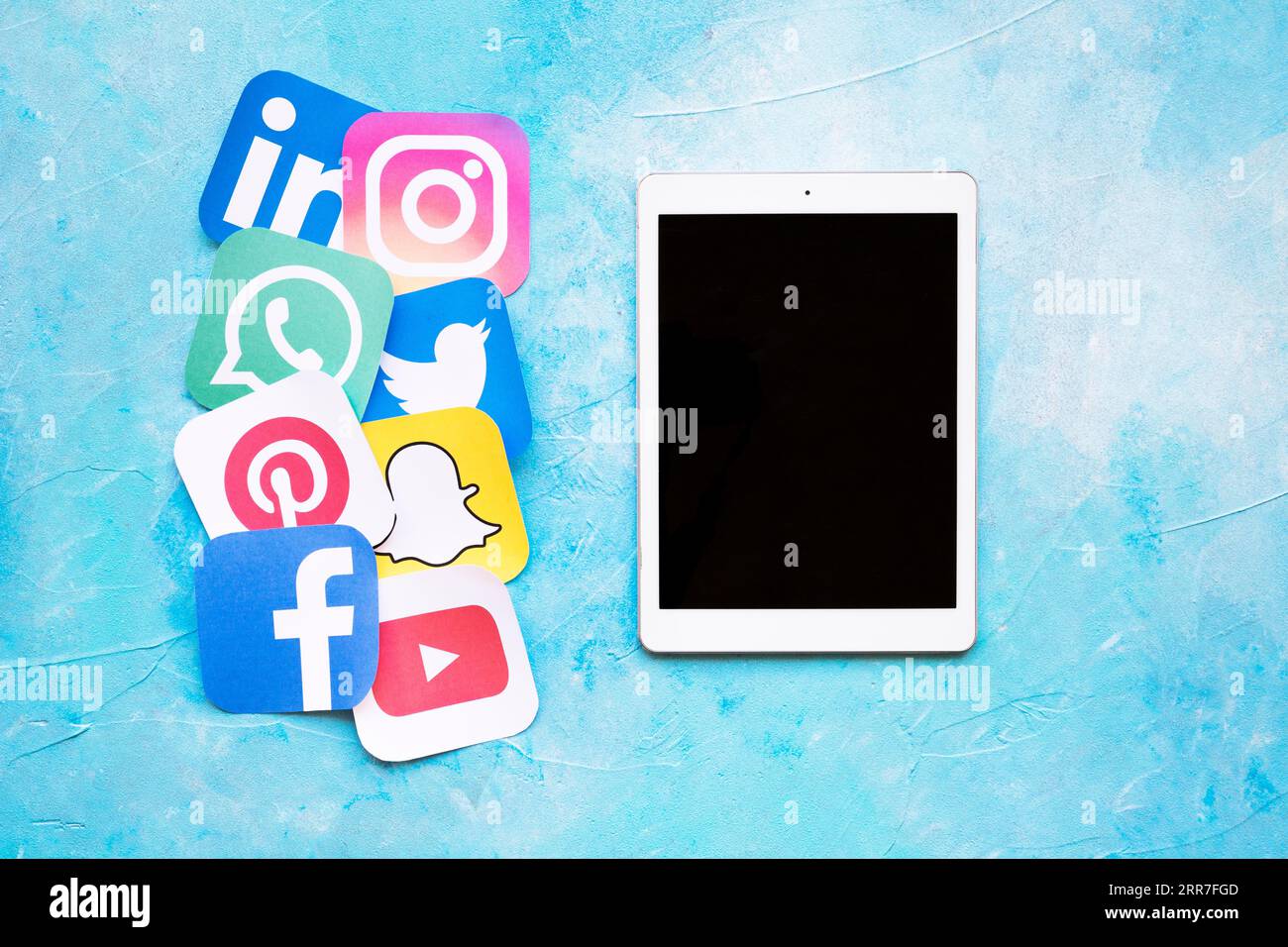 Tablet digitale posizionato vicino alle icone arrotondate ritaglio della carta stampata sui social media Foto Stock