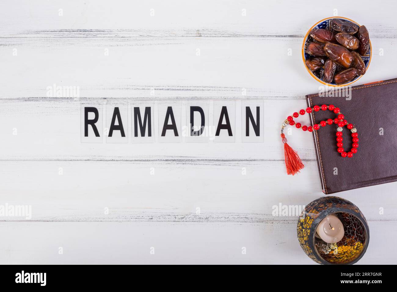 Testo Ramadan con ciotola succosa datteri diario rosso perline di preghiera tavolo bianco Foto Stock