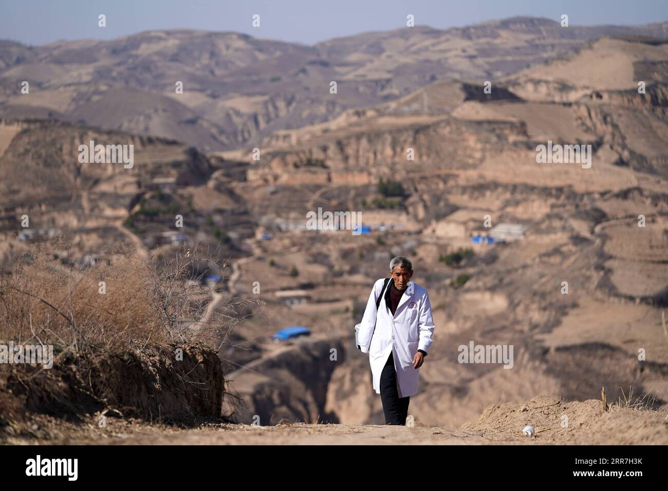 210329 -- TAIYUAN, 29 marzo 2021 -- Zhang Shangbao cammina su un sentiero con il suo kit medico nel villaggio Tietou della contea di Shilou, provincia dello Shanxi della Cina settentrionale, 23 marzo 2021. Zhang, 61 anni, che ha una sola mano, cammina per le montagne giorno dopo giorno dal 1976, salvaguardando la salute della gente del posto. Ci sono più di 600 abitanti del villaggio che vivono in 5 borghi del villaggio di Tietou nascosto tra i monti Lyuliang. In passato, era difficile accedere all'assistenza sanitaria, che aveva afflitto le masse qui per molto tempo. Nel 1976 Zhang Shangbao si è diplomato in una scuola di salute all'età di 16 anni Foto Stock